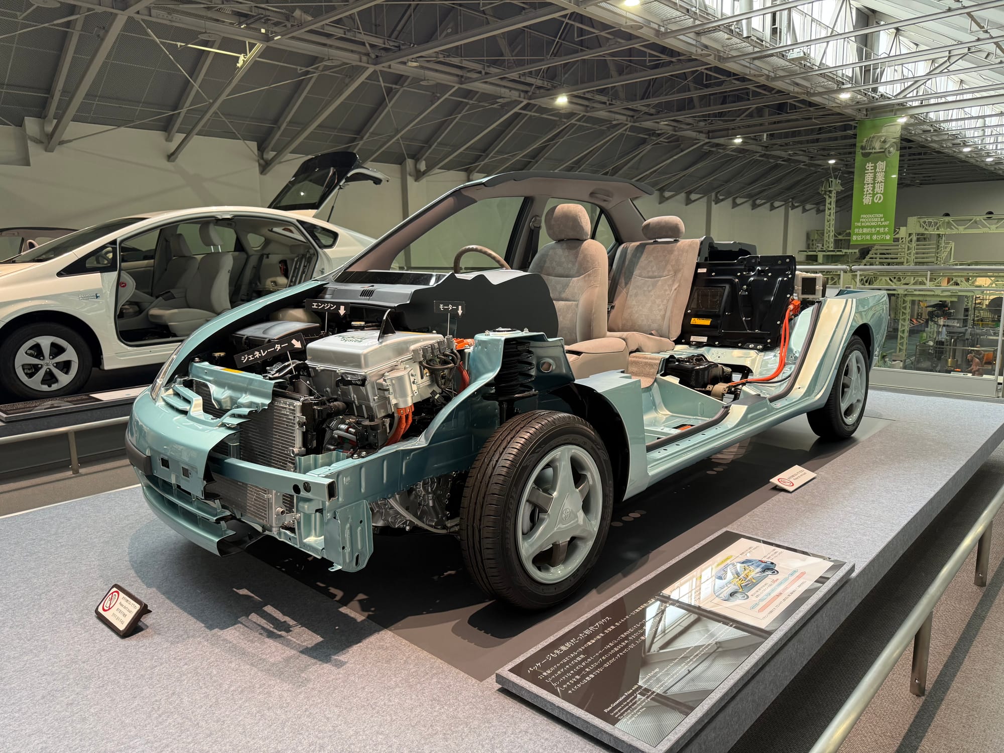Cutaway display of a Toyota Prius hybrid at the Toyota Commemorative Museum of Industry and Technology, revealing the engine, electric motor, battery system and vehicle structure.