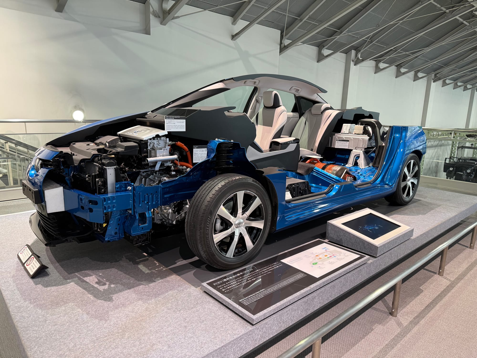 Cutaway display of a Toyota Mirai fuel cell vehicle at the Toyota Commemorative Museum, revealing the hydrogen fuel cell system, electric drivetrain and vehicle structure.