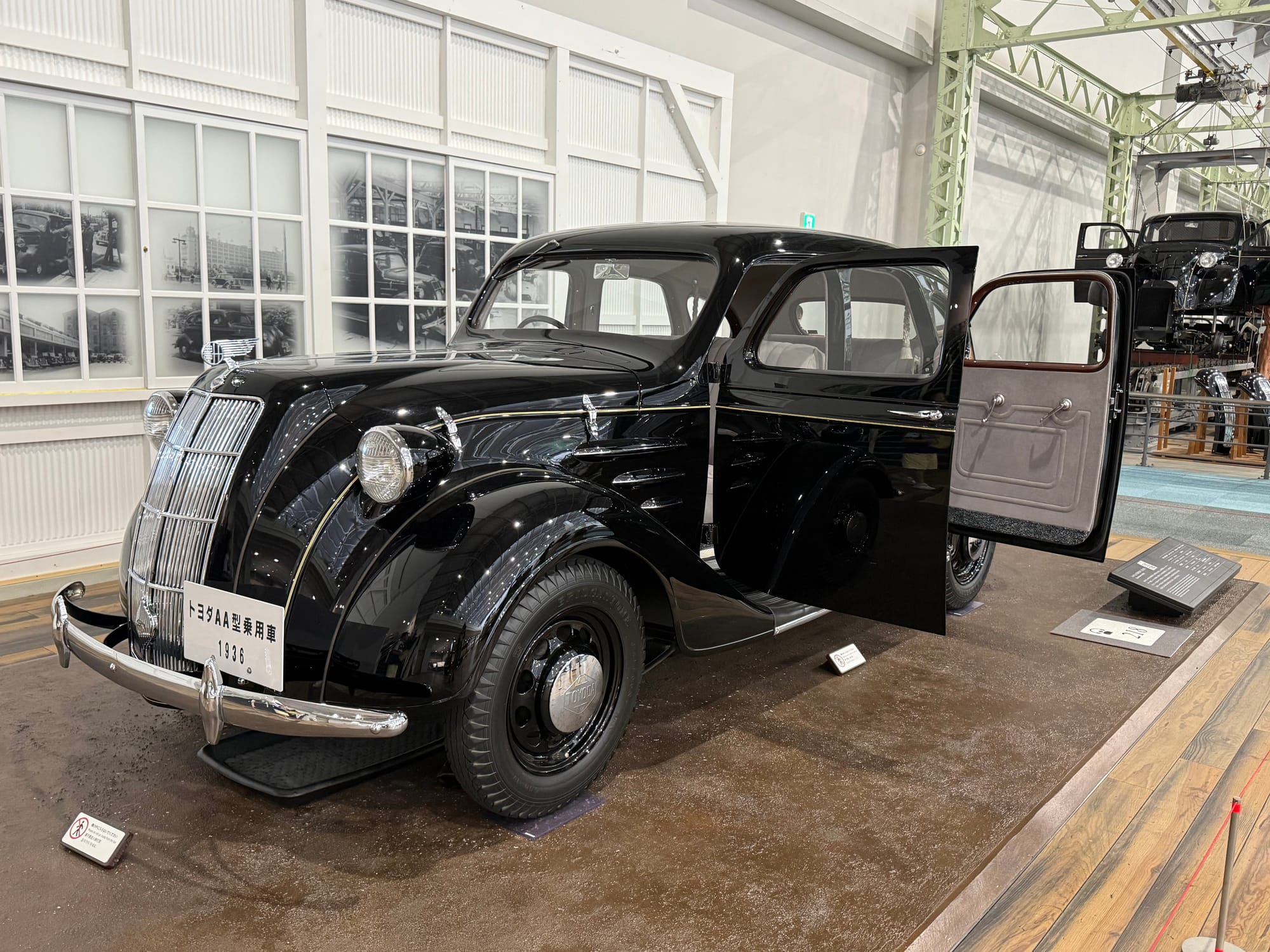 1936 Toyota AA passenger car on display at the Toyota Commemorative Museum of Industry and Technology, featuring streamlined black bodywork and one of Toyota's earliest production vehicles.