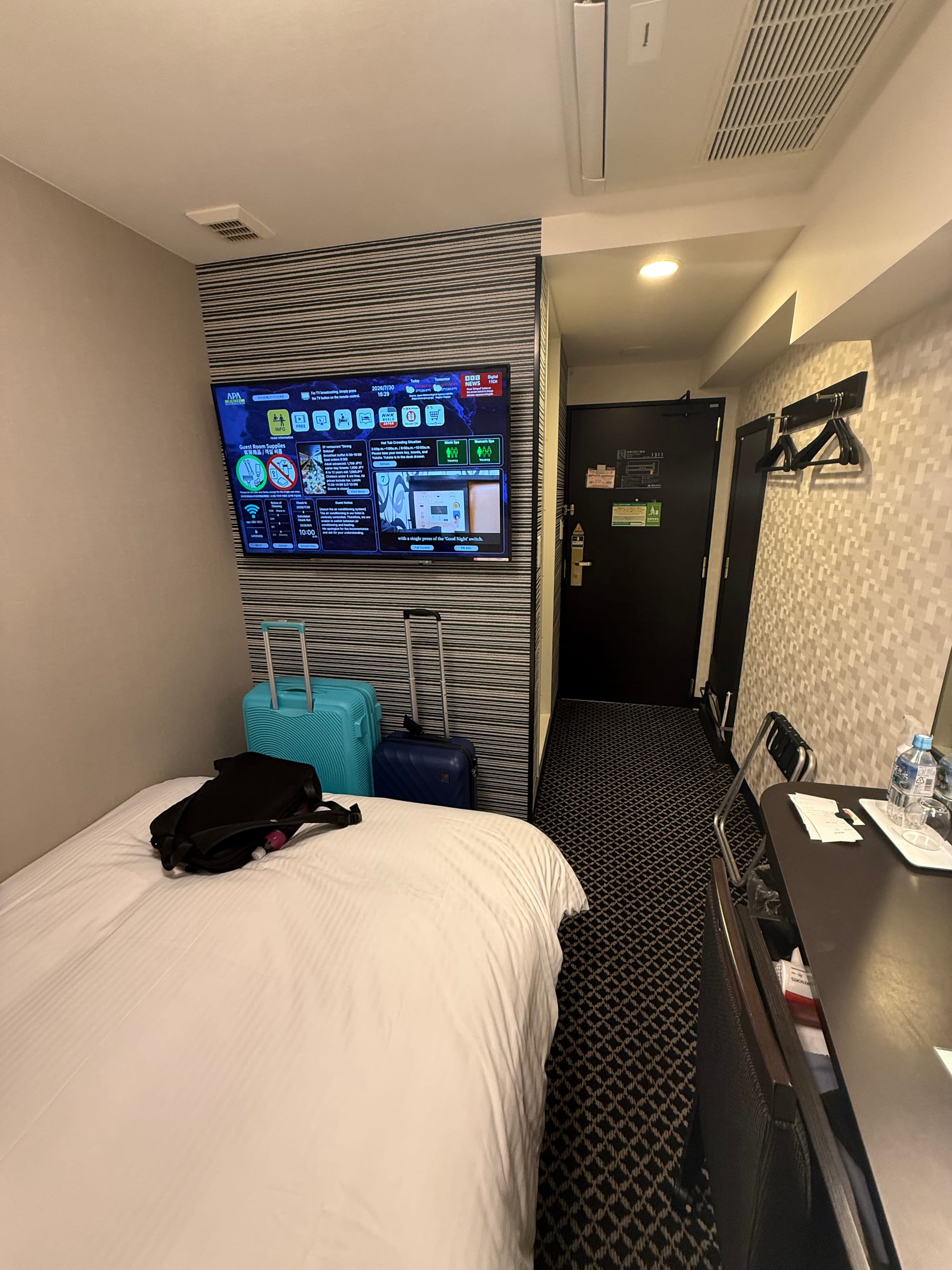 Compact room at APA Hotel Nagoya Sakae-Kita, featuring a double bed, desk, wall-mounted television, luggage and an efficient space-saving layout.