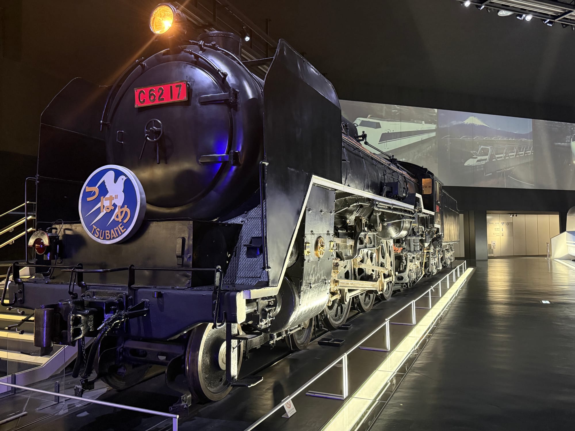 C62 17 steam locomotive displayed at the SCMAGLEV and Railway Park in Nagoya, carrying the Tsubame headboard and illuminated within the museum's railway history gallery.