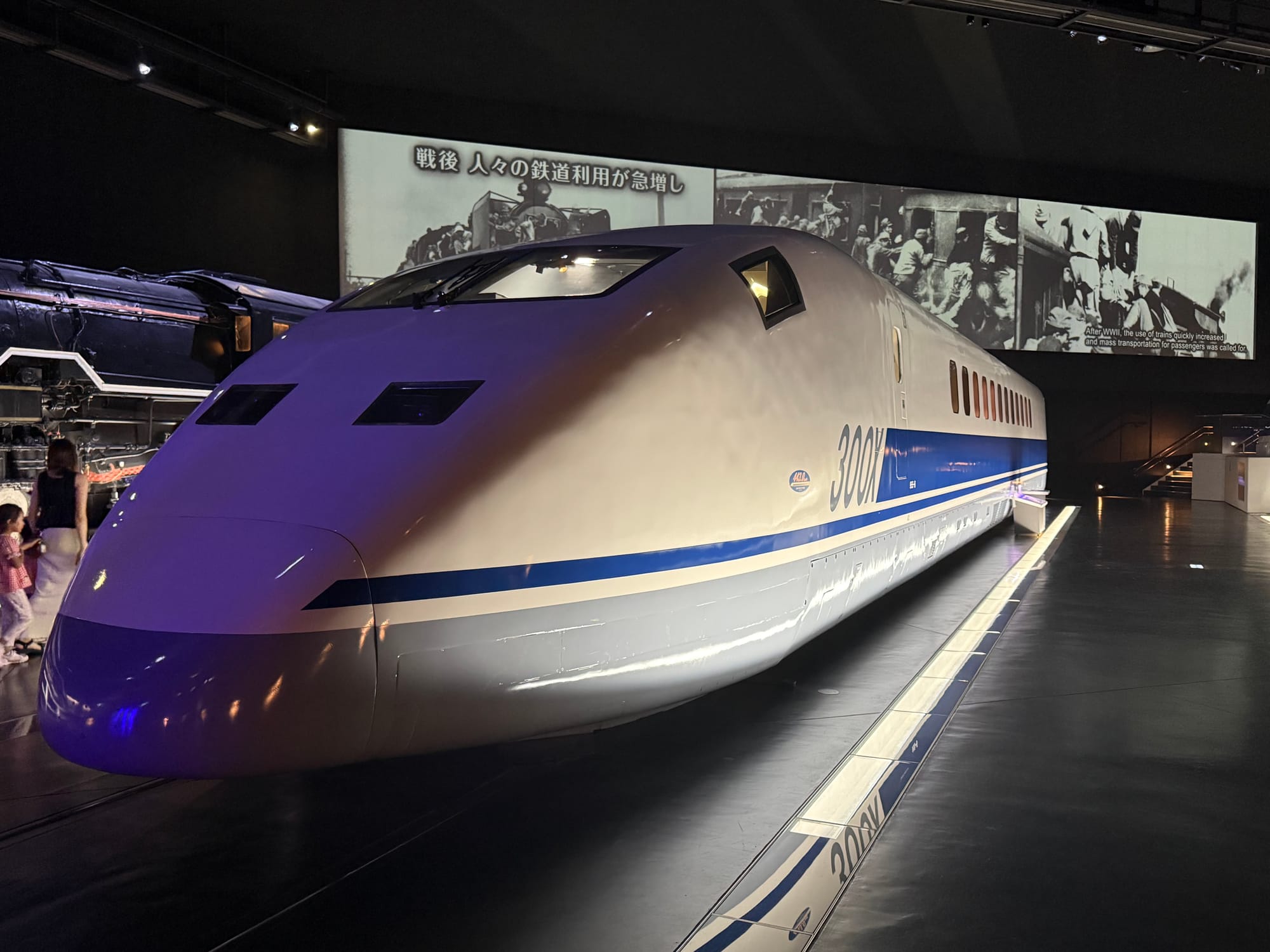 JR Central 300X experimental Shinkansen train displayed at the SCMAGLEV and Railway Park in Nagoya, featuring its aerodynamic nose and blue-striped white bodywork.