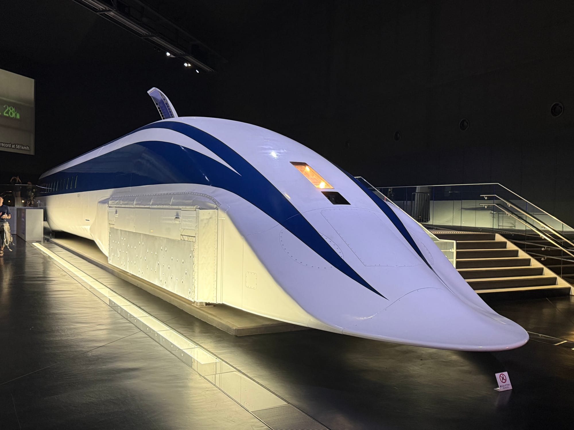 MLX01-1 superconducting maglev test vehicle displayed at the SCMAGLEV and Railway Park in Nagoya, featuring its long aerodynamic nose and blue-striped white bodywork.