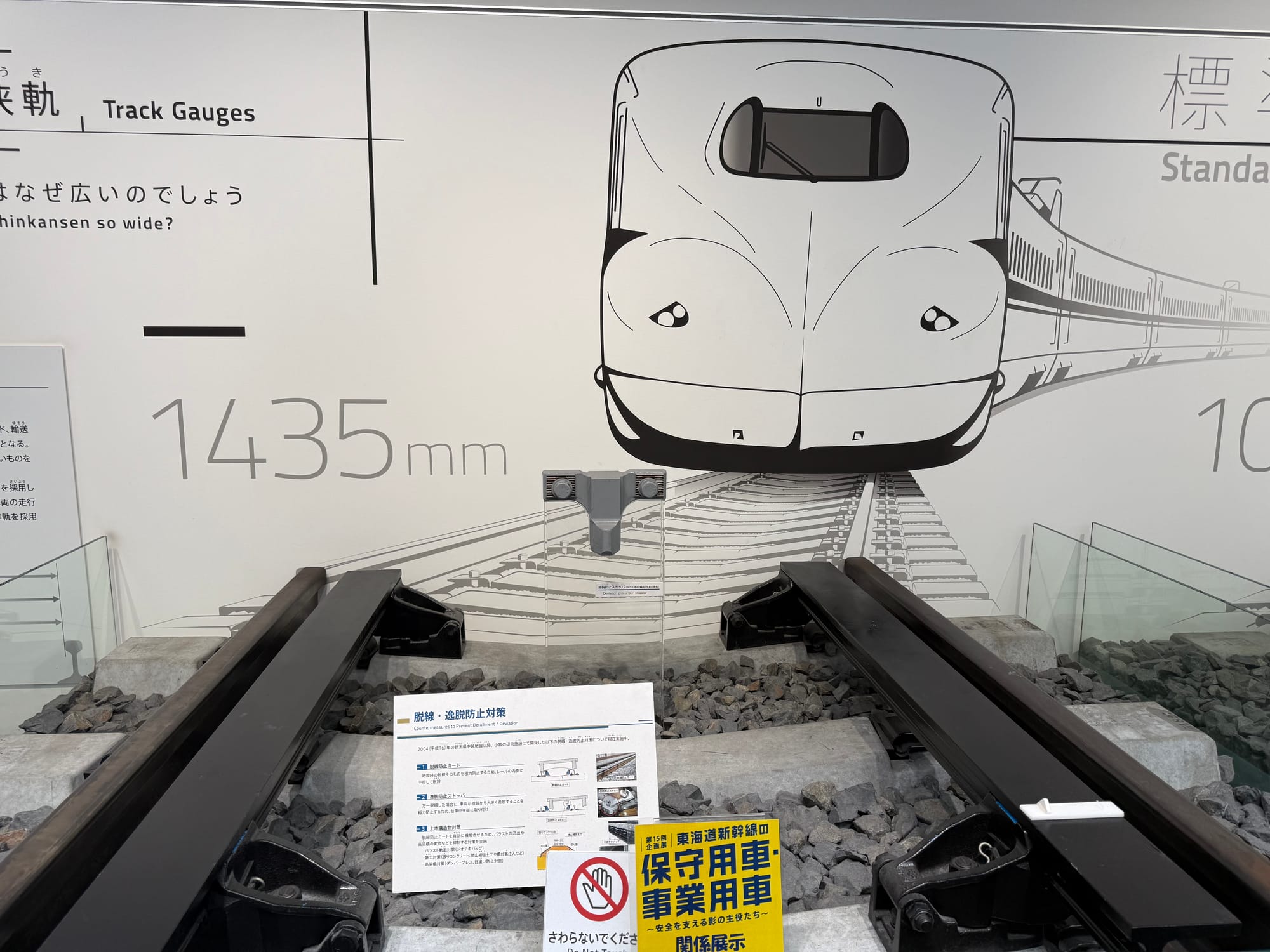 Shinkansen track display at the SCMAGLEV and Railway Park, showing standard gauge rails set 1,435 mm apart beneath a large illustration of a high-speed train.