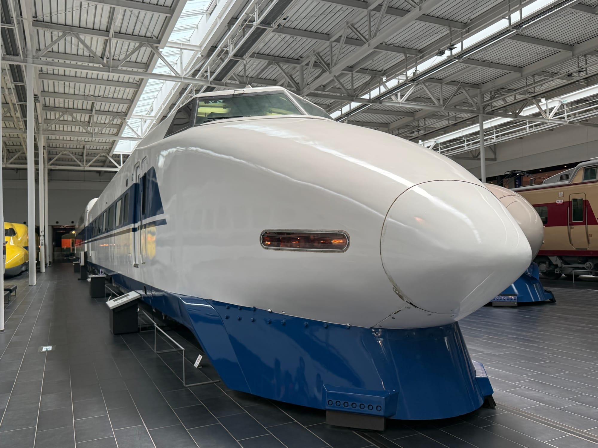 100 Series Shinkansen displayed at the SCMAGLEV and Railway Park in Nagoya, featuring its distinctive pointed nose, blue-and-white livery and double-deck design.