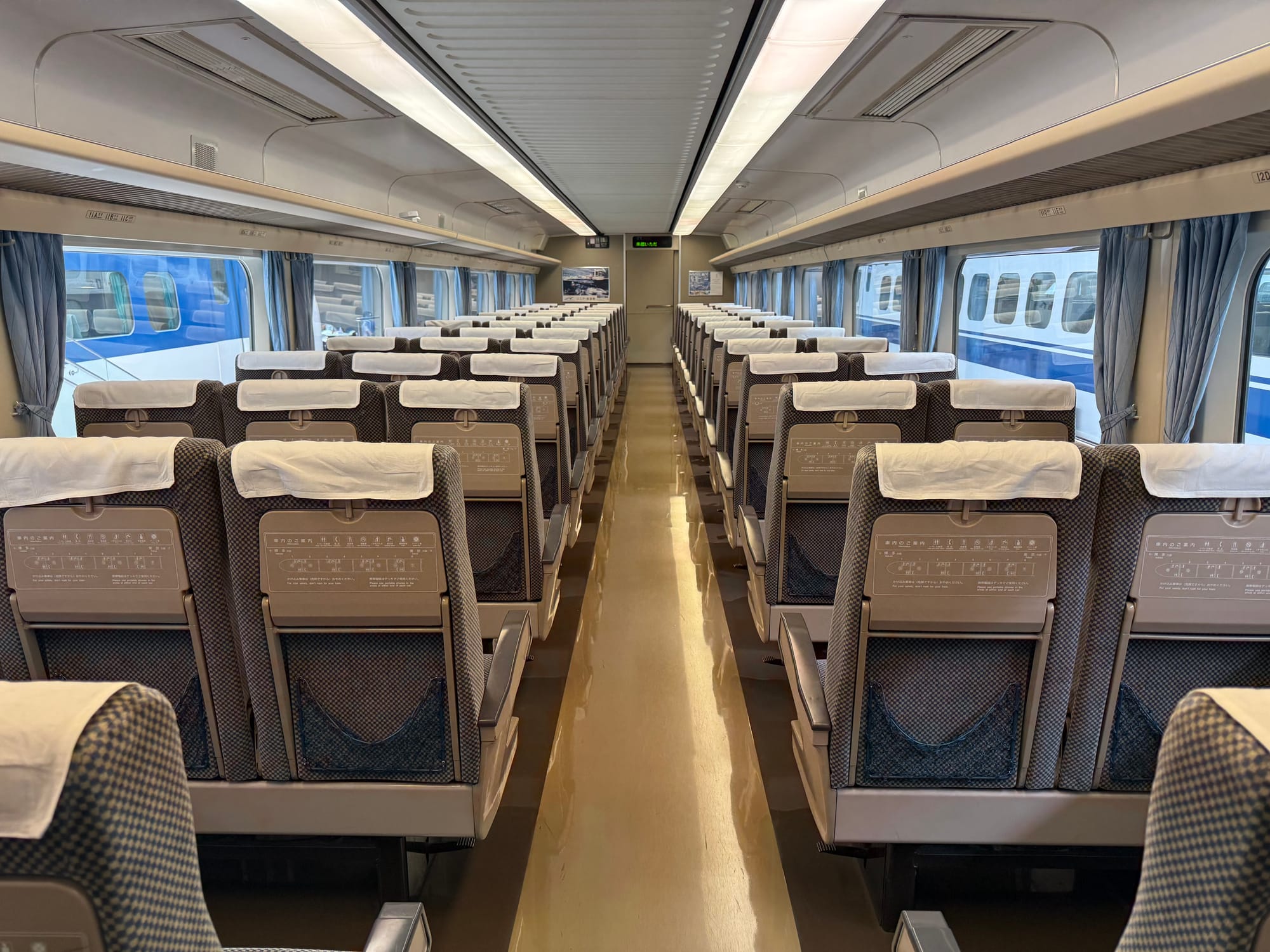 Interior of a 0 Series Shinkansen carriage at the SCMAGLEV and Railway Park, showing rows of original seats, large windows and the spacious layout of Japan's first high-speed train.