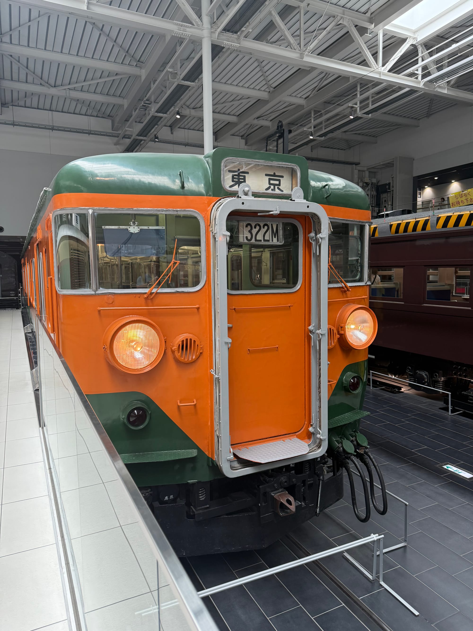 JNR 111 Series suburban electric train displayed at the SCMAGLEV and Railway Park in Nagoya, featuring its distinctive orange-and-green "Shōnan" livery and Tokyo destination sign.