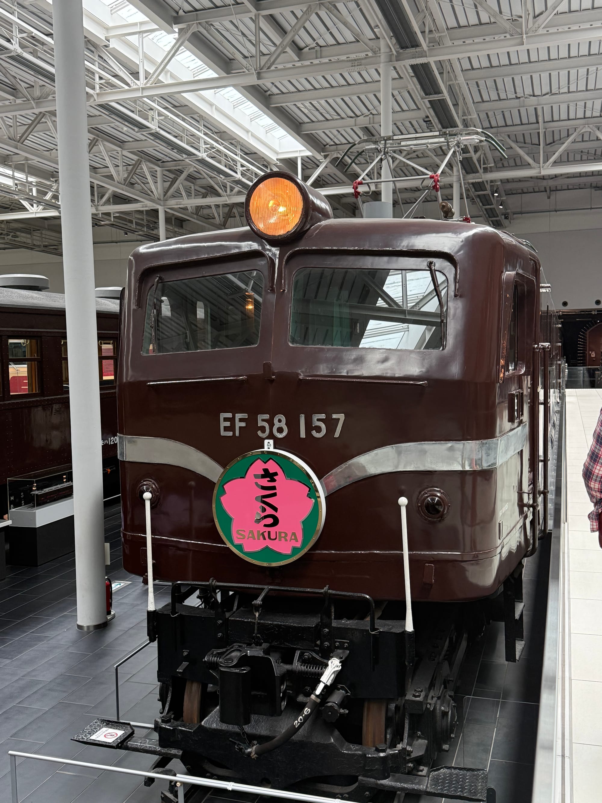 EF58 157 electric locomotive displayed at the SCMAGLEV and Railway Park in Nagoya, carrying a pink Sakura headboard and finished in traditional brown livery.
