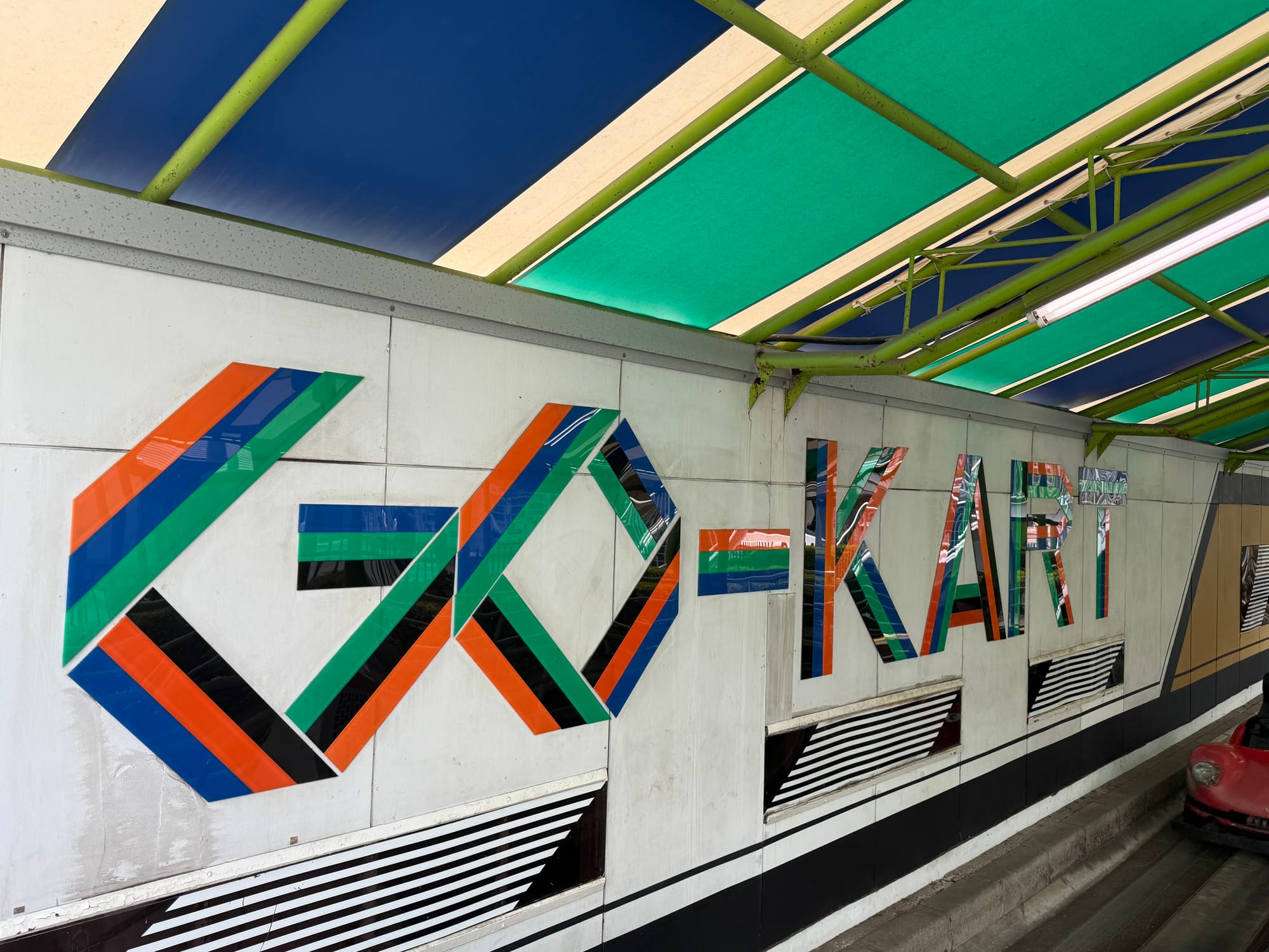Sign for Go-Kart at Nagashima Spa Land, featuring colourful geometric lettering mounted beneath a striped canopy above the entrance to the attraction.