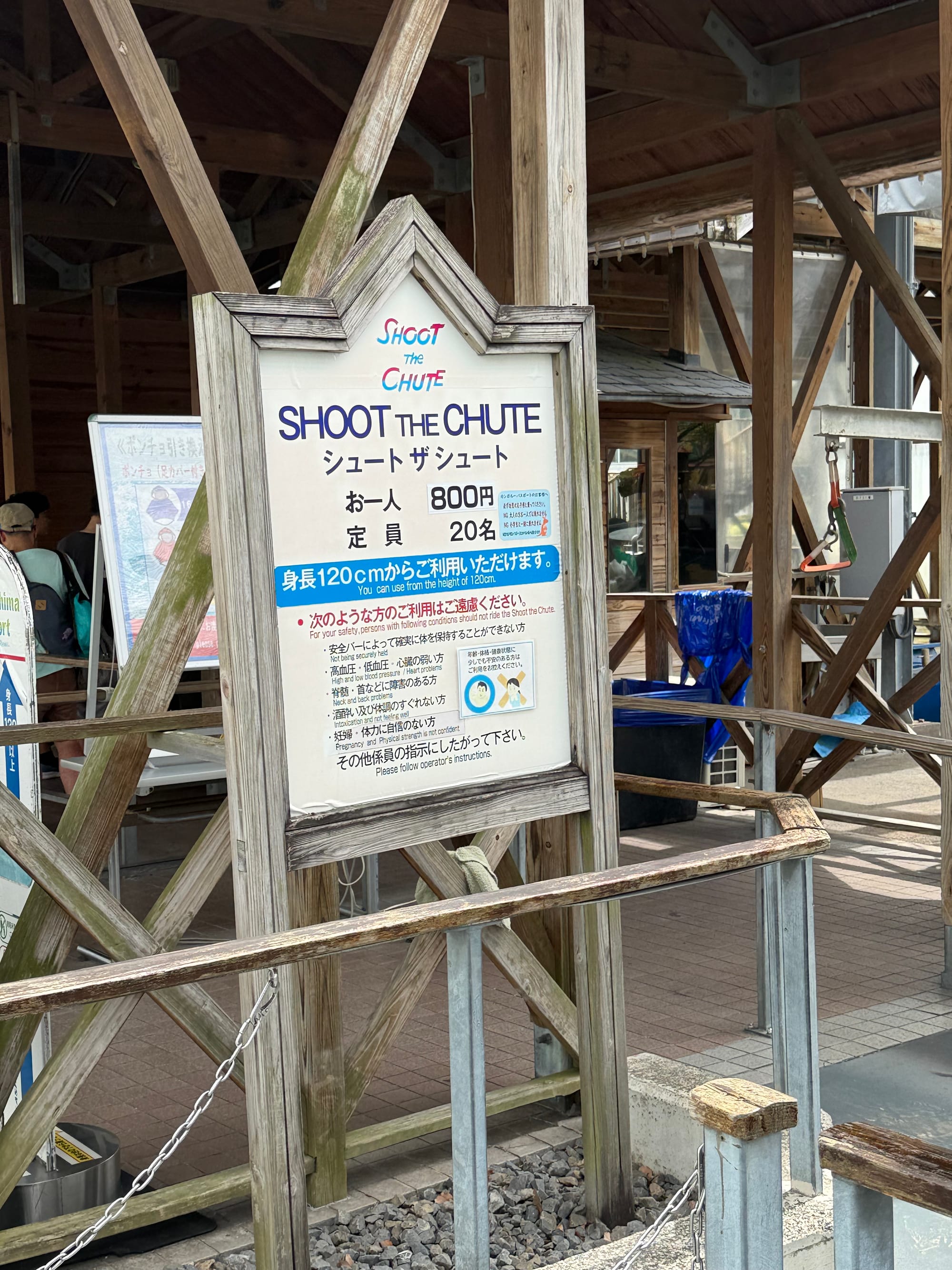 Sign for Shoot the Chute at Nagashima Spa Land, displaying ride information, height requirements and safety notices beside the entrance to the classic water ride.