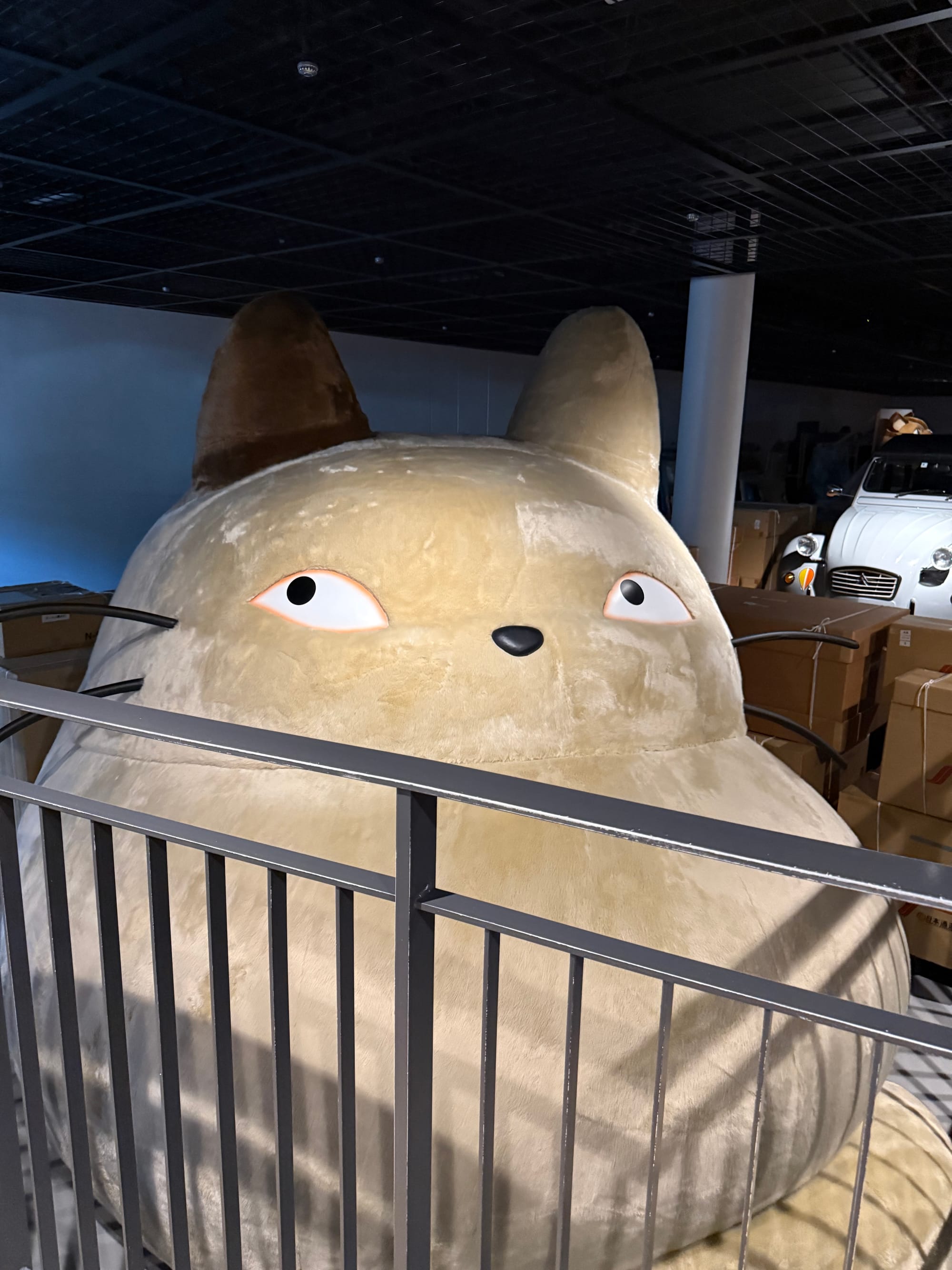 Giant Totoro figure displayed inside the Grand Warehouse at Ghibli Park, surrounded by crates and props that recreate the memorable scene from My Neighbour Totoro.
