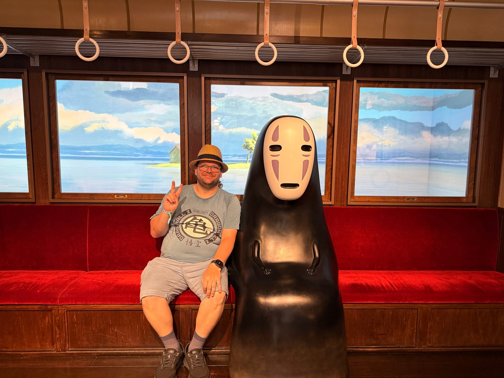 Taking a seat beside No-Face on the iconic train from Spirited Away in the Becoming Characters in Memorable Ghibli Scenes exhibit, one of the most popular experiences inside Ghibli Park's Grand Warehouse.