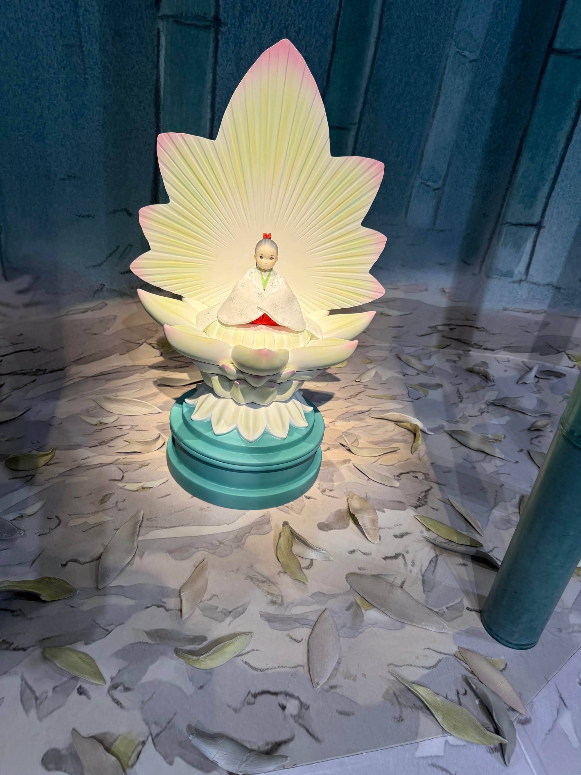 Princess Kaguya sits inside a glowing lotus flower in a display from The Tale of the Princess Kaguya at Ghibli Park's Grand Warehouse, surrounded by fallen petals.