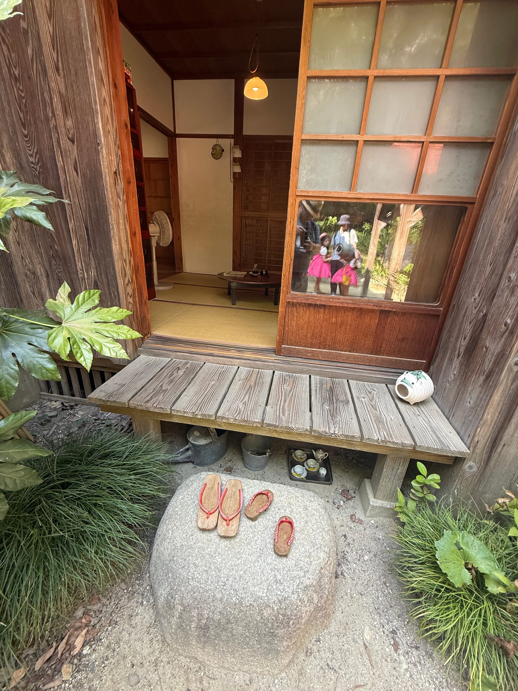 Satsuki and Mei's House from My Neighbour Totoro at Ghibli Park, featuring a white wooden exterior, steep red roof, open veranda and surrounding woodland.