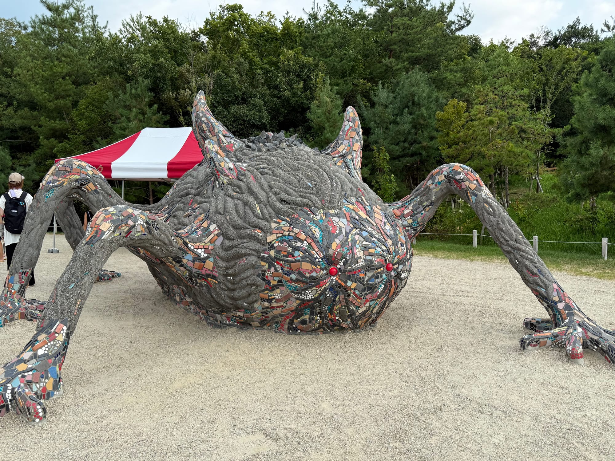 Mosaic sculpture of the demon Nago from Princess Mononoke at Ghibli Park, featuring red eyes, sprawling limbs and colourful tiled detailing across its cursed form.