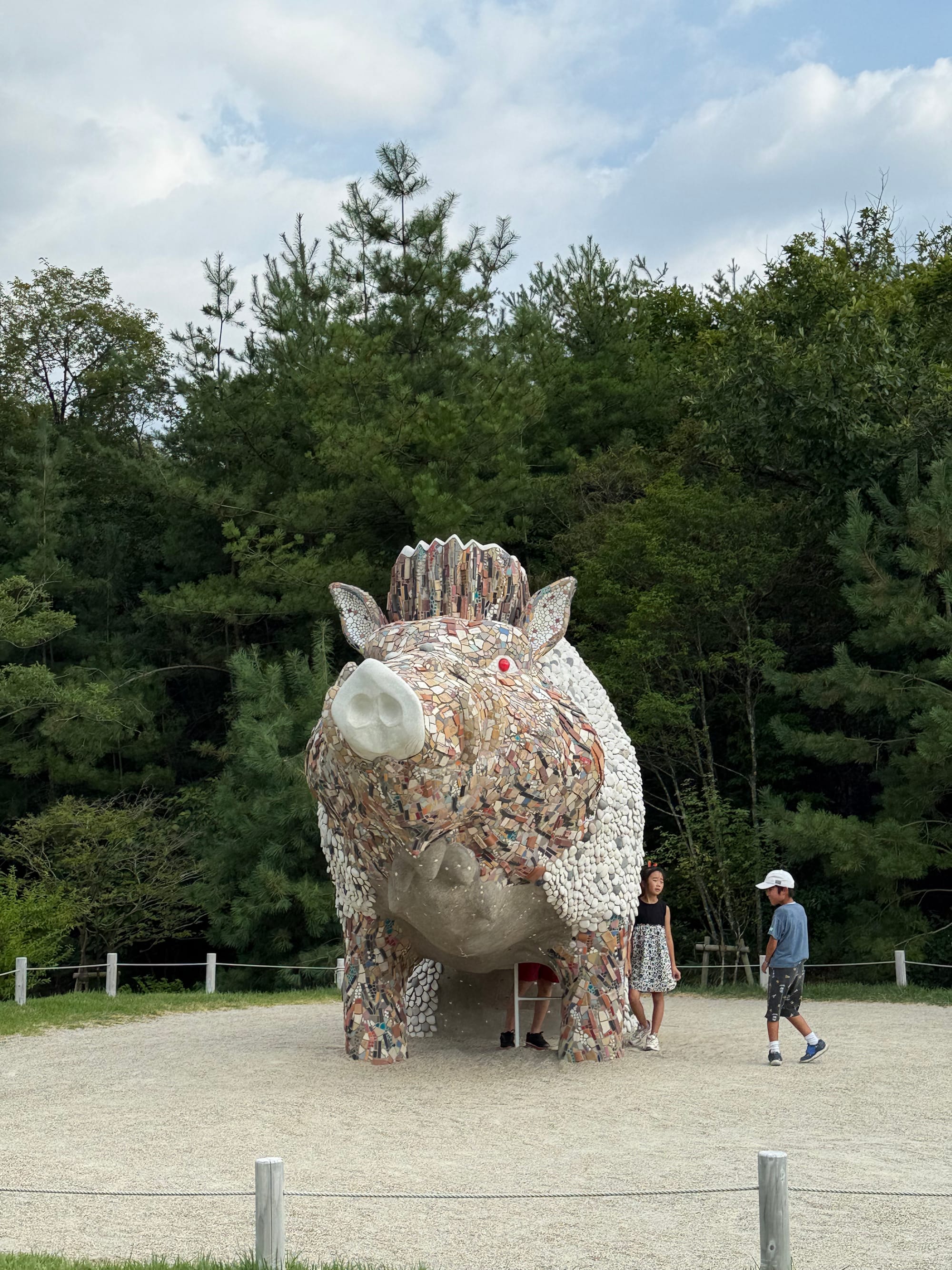 Mosaic sculpture of Okkoto, the giant boar god from Princess Mononoke, at Ghibli Park, featuring red eyes, white tusks and a richly textured tiled surface.