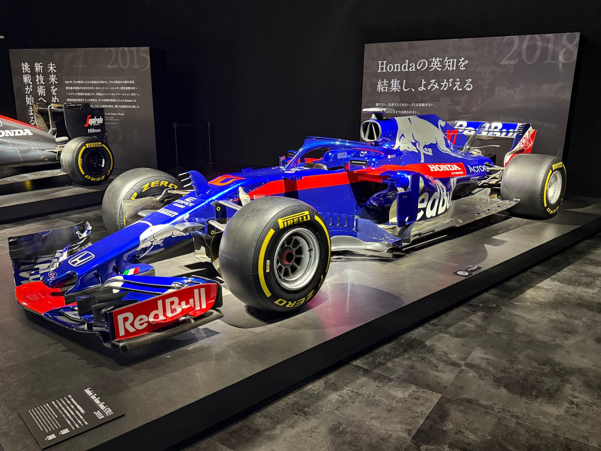 Scuderia Toro Rosso STR13 Formula One car displayed at the Honda Racing Gallery, featuring Honda branding, Red Bull sponsorship and the blue-and-red livery from the 2018 season.