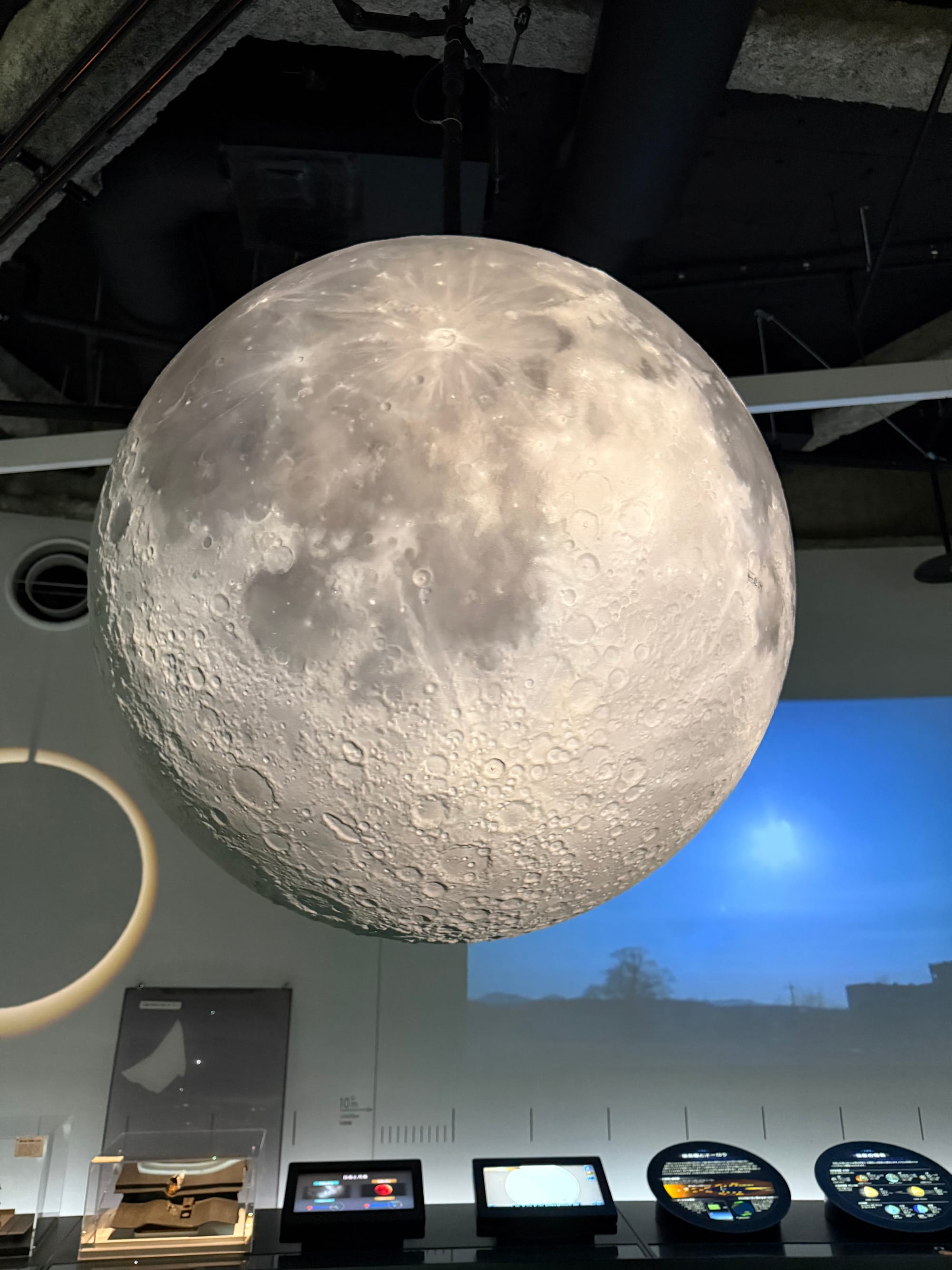 Large suspended model of the Moon displayed at the Nagoya City Science Museum, showing detailed craters, maria and surface features illuminated from above.