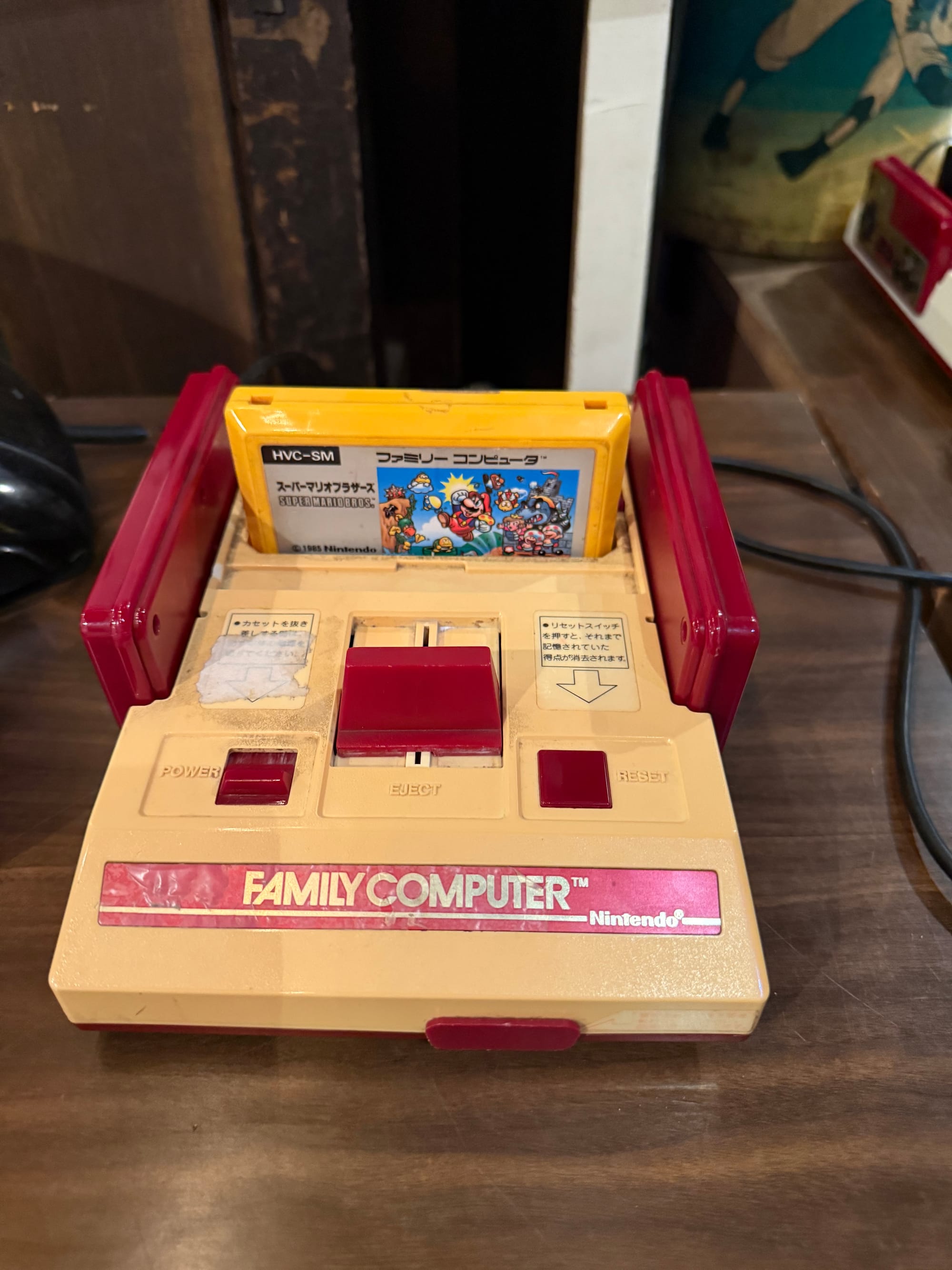 Nintendo Family Computer (Famicom) console displayed at the Takayama Showa-kan Museum, with a Super Mario Bros. cartridge inserted into the classic red-and-cream game system.