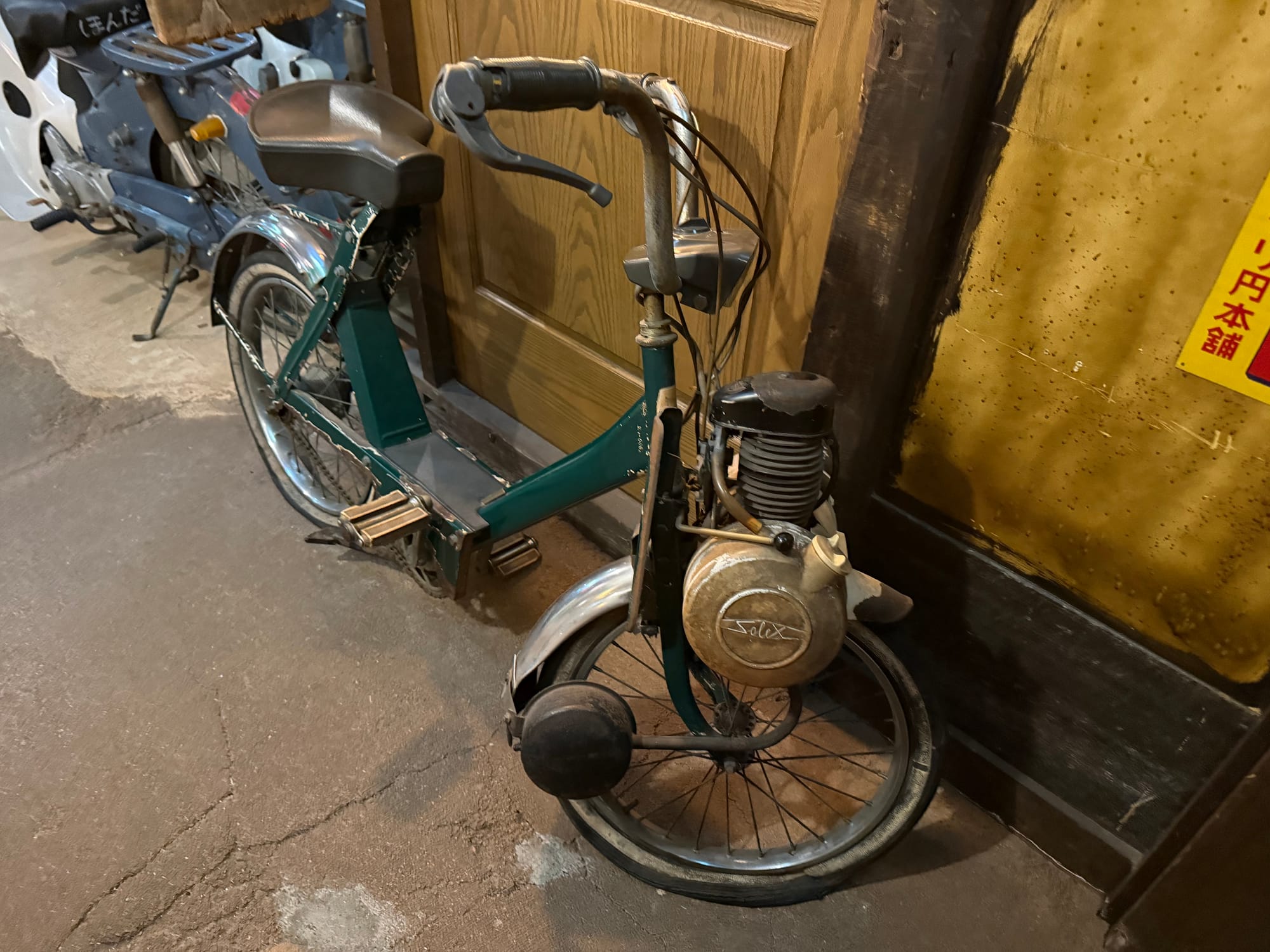 Vintage Solex motorised bicycle displayed at the Takayama Showa-kan Museum, featuring a front-mounted engine, step-through frame and small wheels typical of mid-20th-century transport.