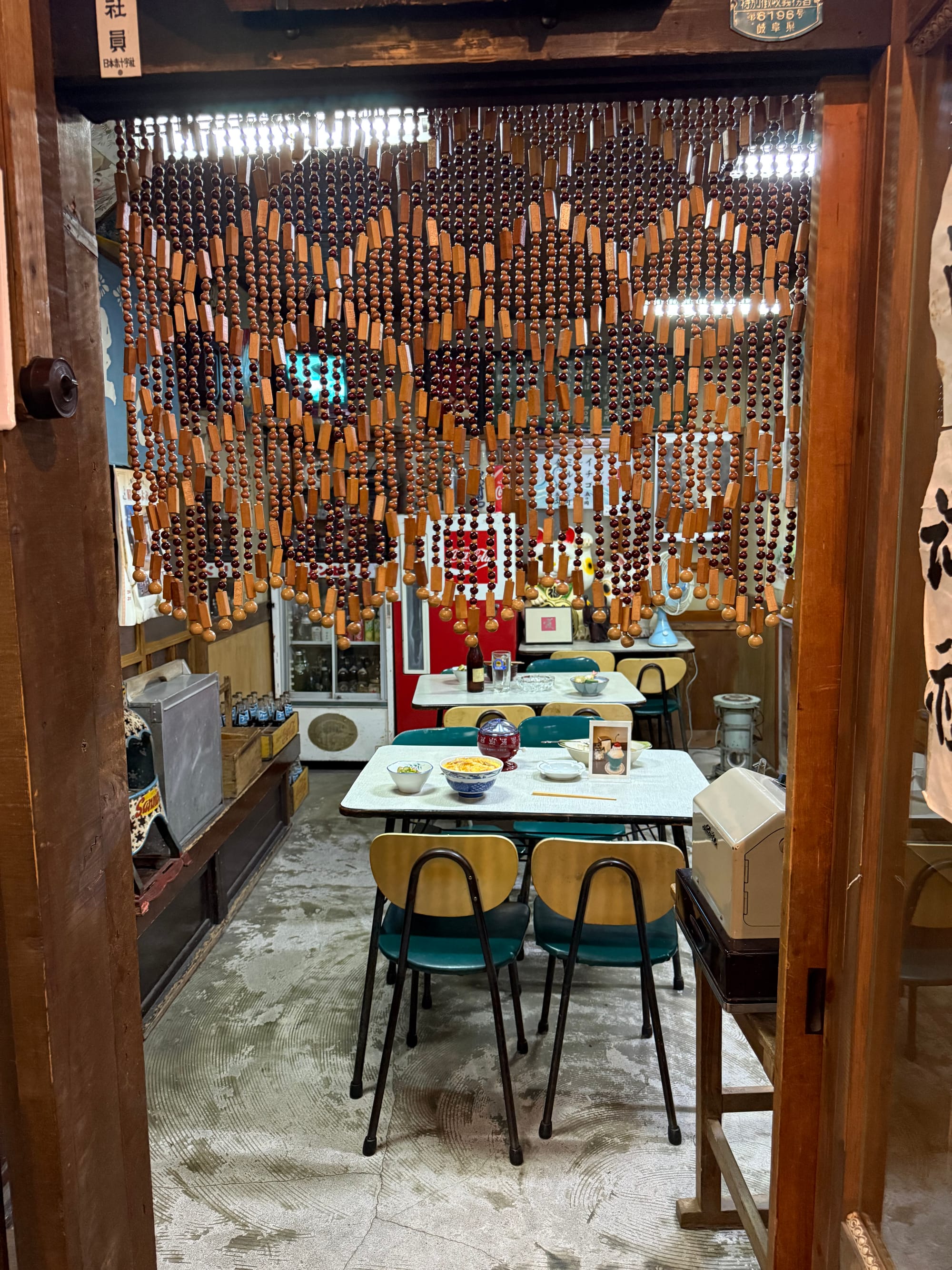 Recreated Showa-era diner inside the Takayama Showa-kan Museum, featuring vintage tables and chairs, bead curtains, replica meals and period restaurant décor.