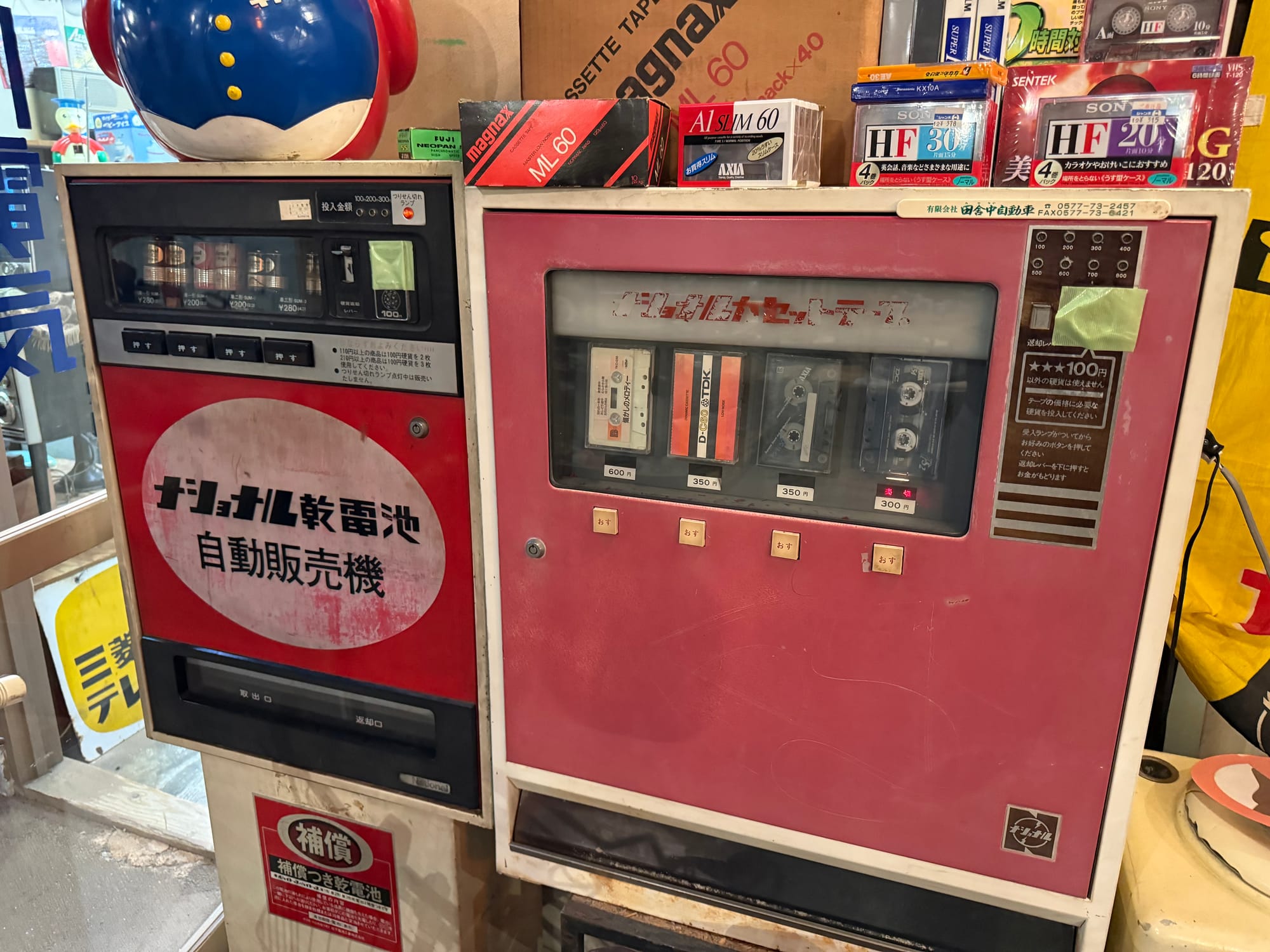 Vintage vending machines at the Takayama Showa-kan Museum, including machines for cassette tapes and batteries, surrounded by retro packaging and nostalgic Showa-era products.