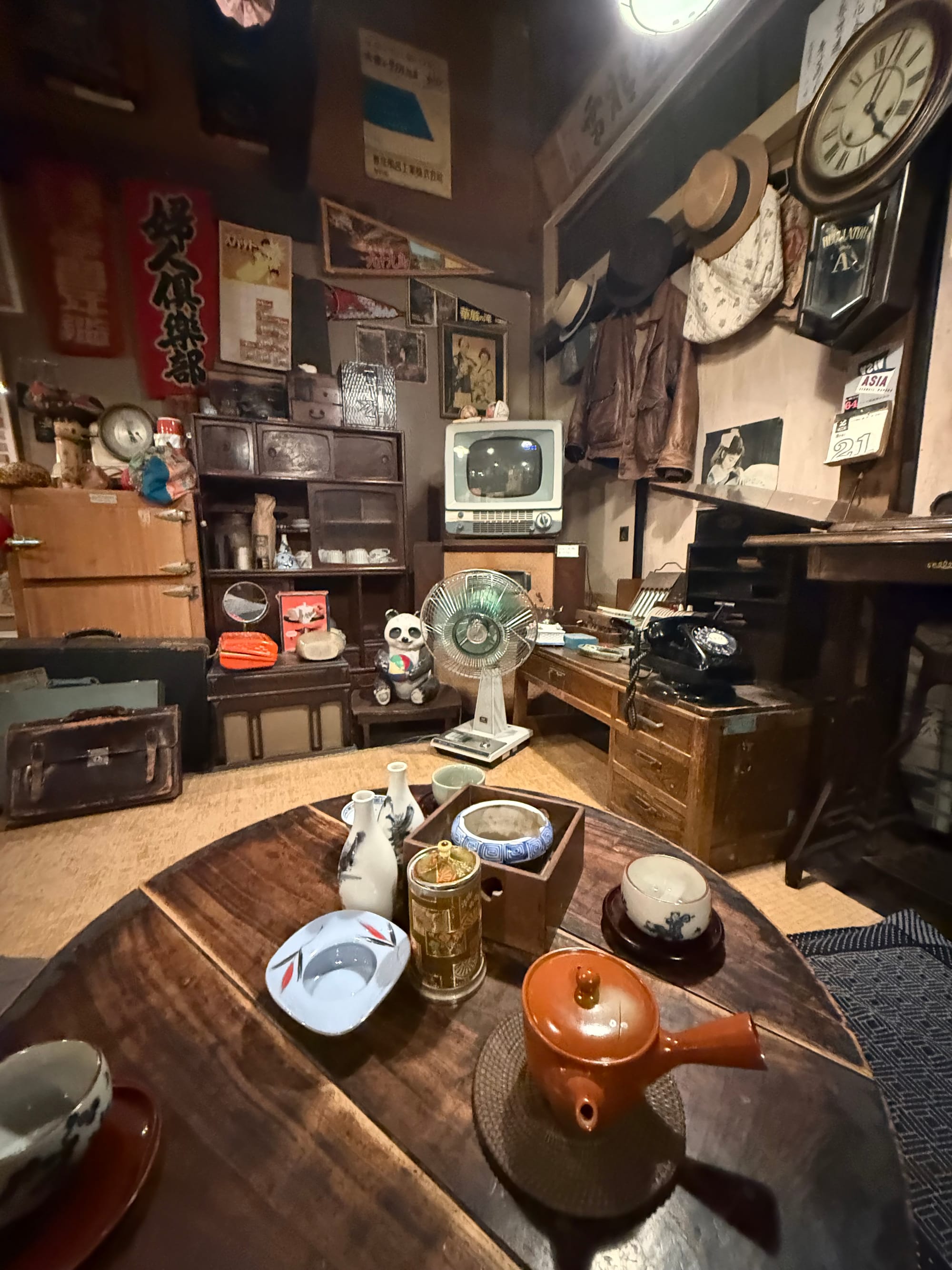 Recreated Showa-era living room at the Takayama Showa-kan Museum, featuring a low table, television, electric fan, rotary telephone, clock and vintage household furnishings.
