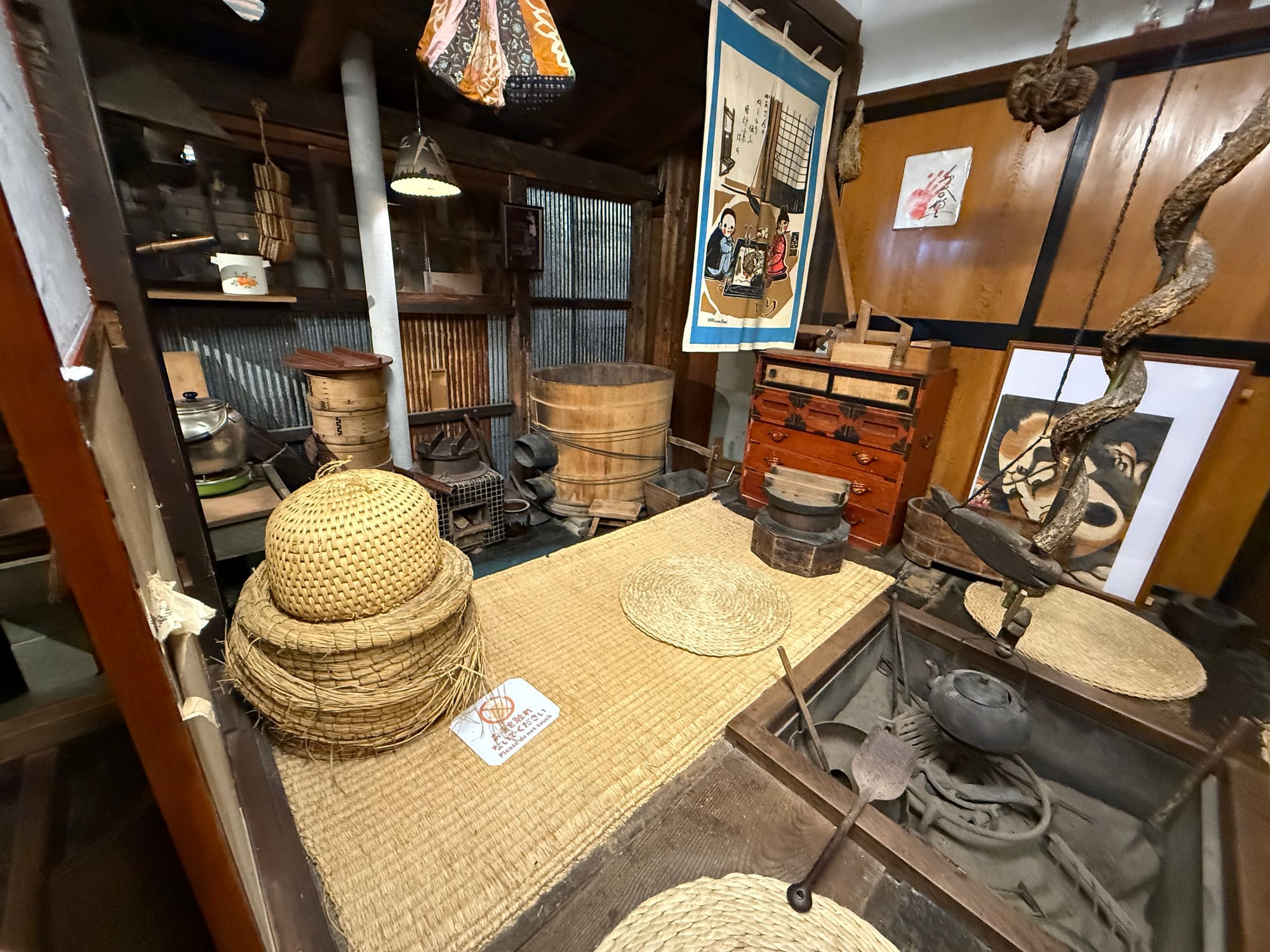 Traditional Japanese farmhouse interior recreated at the Takayama Showa-kan Museum, featuring a sunken hearth, woven baskets, wooden furniture and everyday household tools.