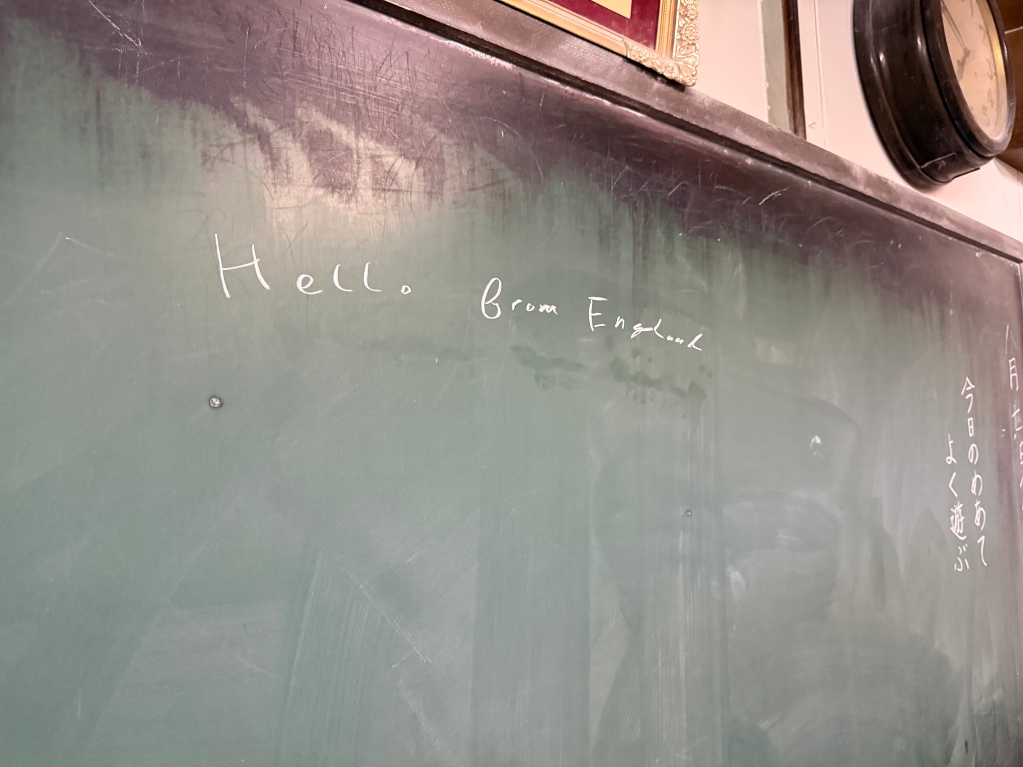Blackboard in a recreated Showa-era classroom at the Takayama Showa-kan Museum, featuring chalk writing in English and Japanese left by museum visitors