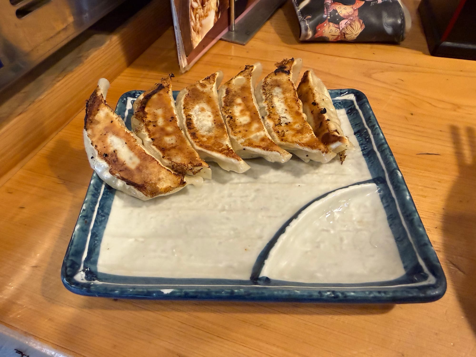 Plate of pan-fried gyoza dumplings served at a restaurant in Takayama, featuring six golden-brown dumplings arranged on a rectangular ceramic plate.