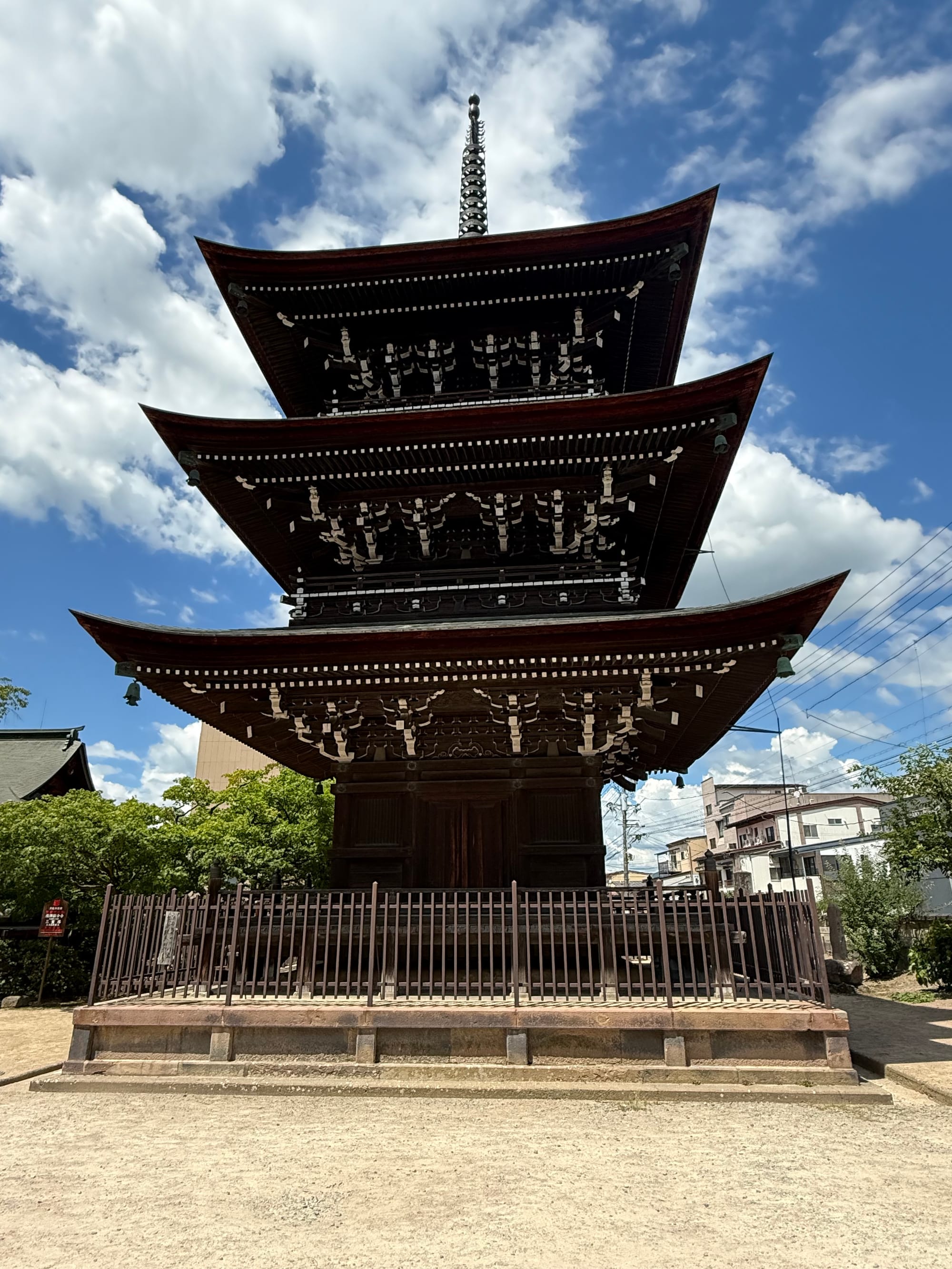 Three-storey wooden pagoda at Hida Kokubun-ji Temple in Takayama, featuring elegant overhanging eaves, a central spire and traditional Buddhist architecture beneath a cloud-filled sky.