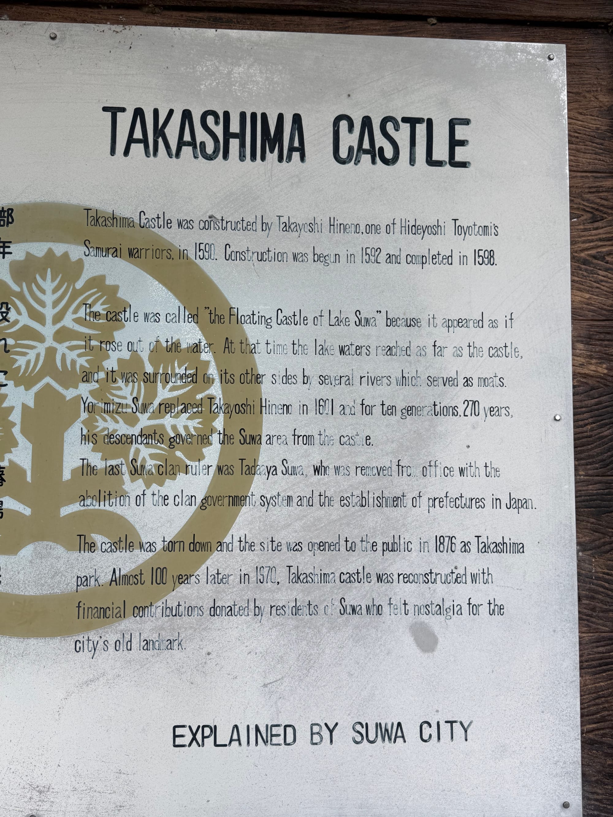 Interpretive sign at Takashima Castle describing the castle's history, construction, reconstruction and nickname, the "Floating Castle of Lake Suwa", with English and Japanese text.