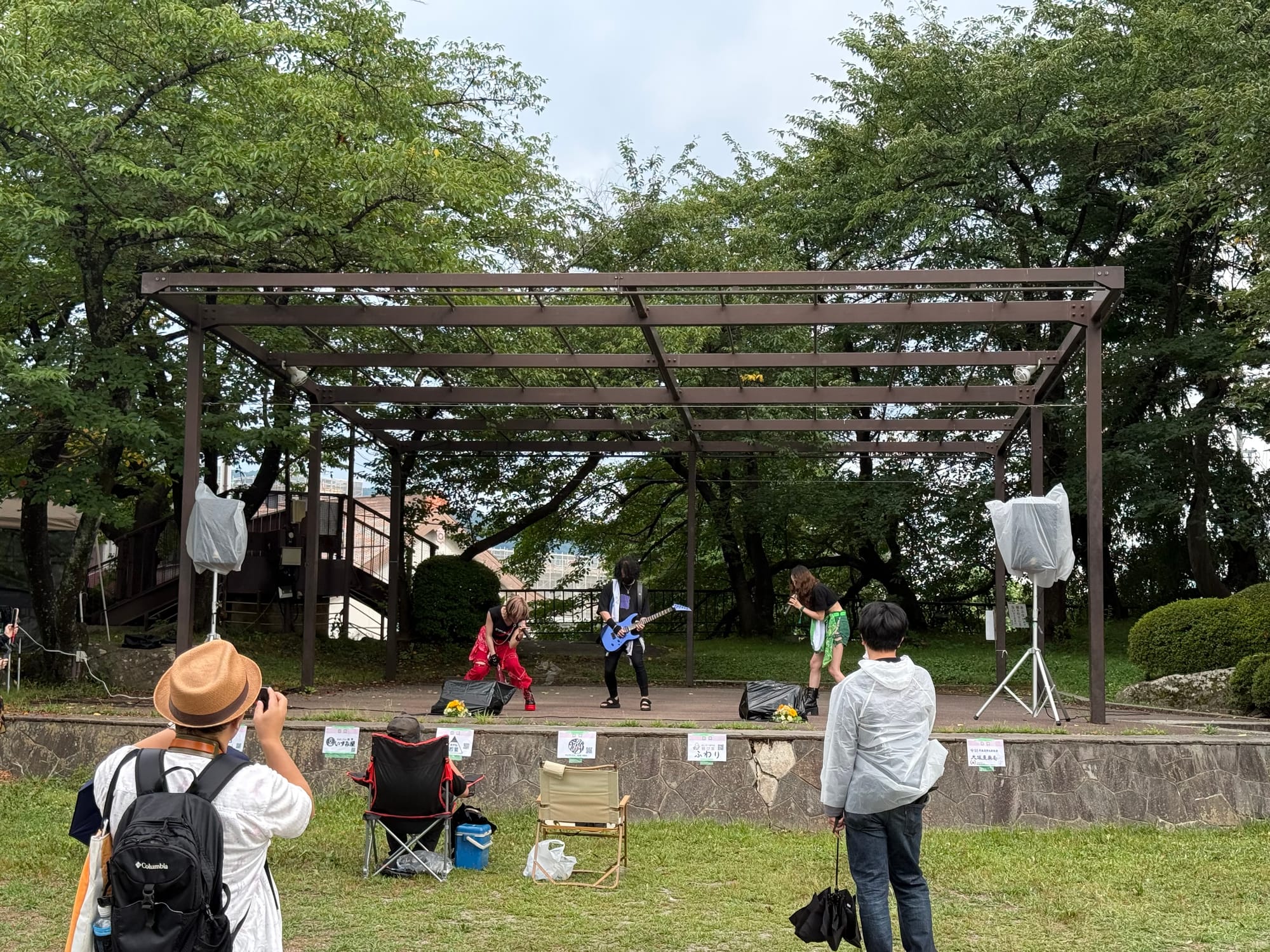 Live music performance at Takashima Castle Fes in Suwa, with musicians performing on an outdoor stage while visitors watch from the lawn beneath overcast skies.