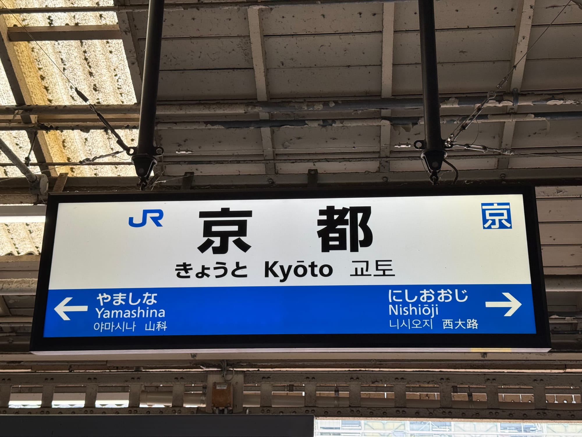 JR Kyoto Station platform sign displaying the station name in Japanese, English and Korean, with arrows indicating the neighbouring stations of Yamashina and Nishiōji.