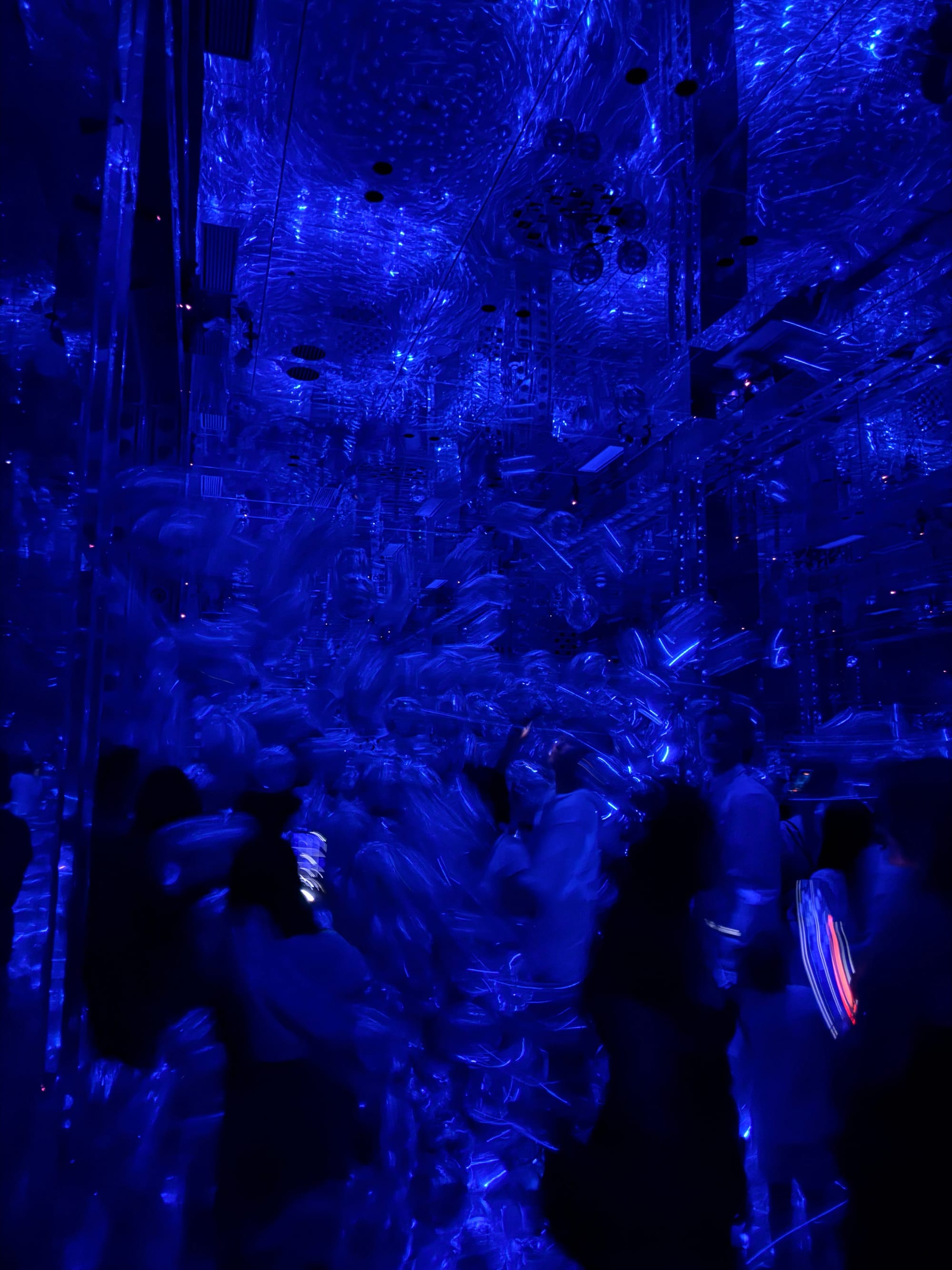 Visitors explore teamLab's Morphing Continuum installation in Kyoto, surrounded by floating translucent forms, mirrors and deep blue lighting that transforms the space.