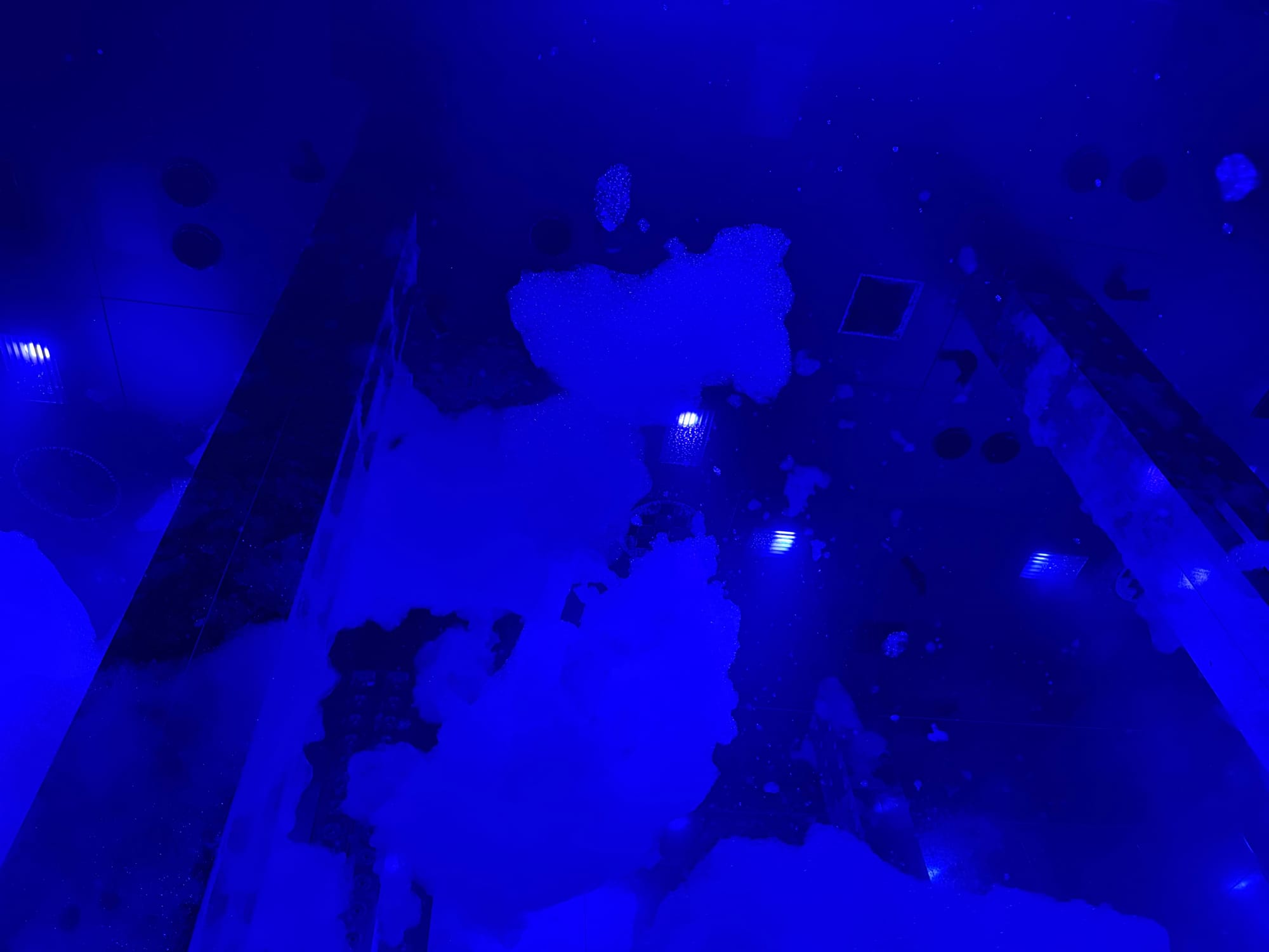 Massless Amorphous Sculpture at teamLab Biovortex Kyoto, featuring floating cloud-like forms illuminated in deep blue light and reflected across mirrored surfaces.