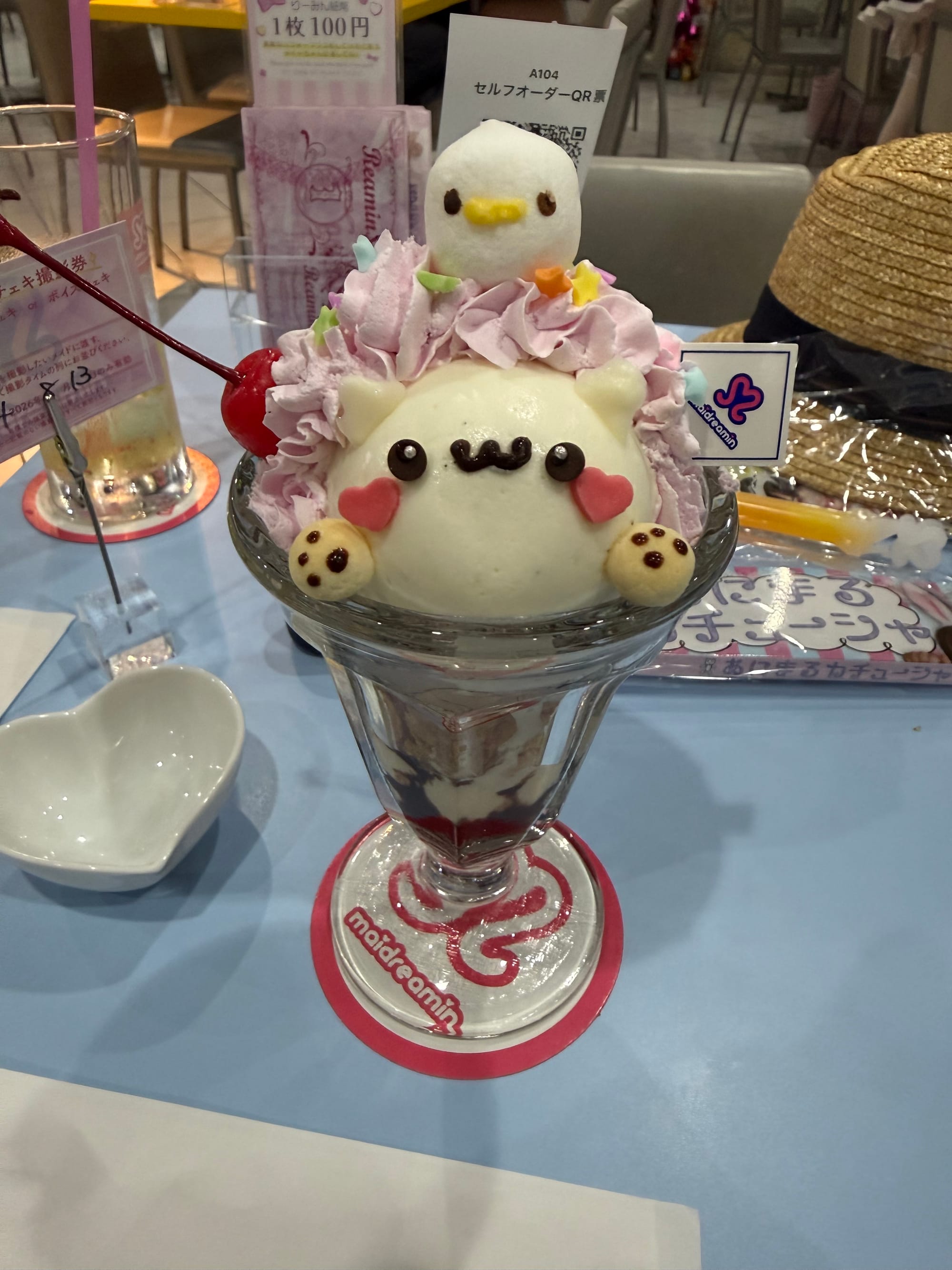 Character-themed parfait at maidreamin Namba in Osaka, topped with whipped cream, ice cream, a cherry, colourful decorations and cute confectionery shaped like animals.