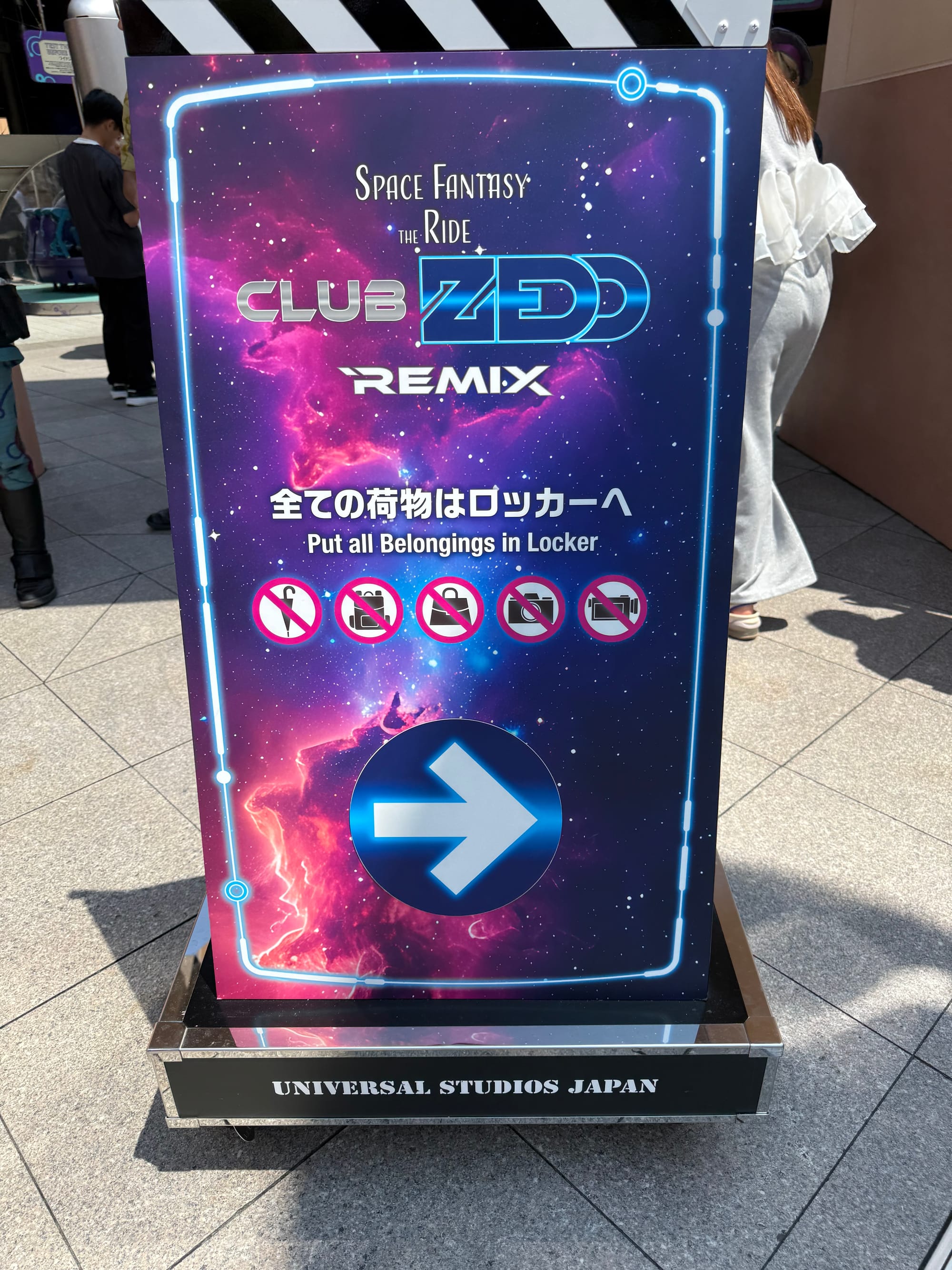 Sign for Space Fantasy: The Ride x CLUB ZEDD Remix at Universal Studios Japan, featuring a galaxy-themed design, attraction branding and guest instructions for locker use.
