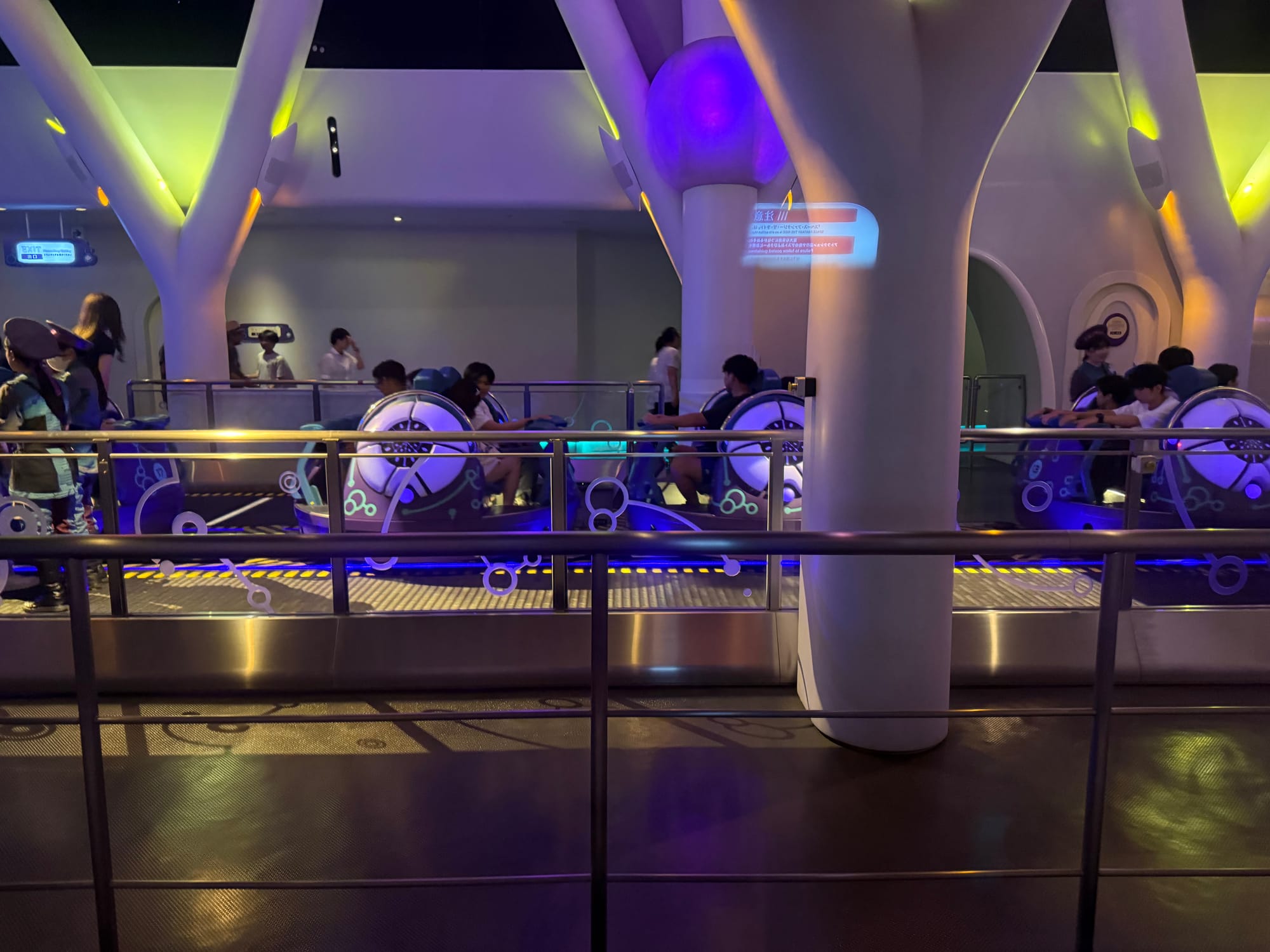 Ride vehicles in the station for Space Fantasy: The Ride x CLUB ZEDD Remix at Universal Studios Japan, illuminated by futuristic blue and purple lighting before departure.