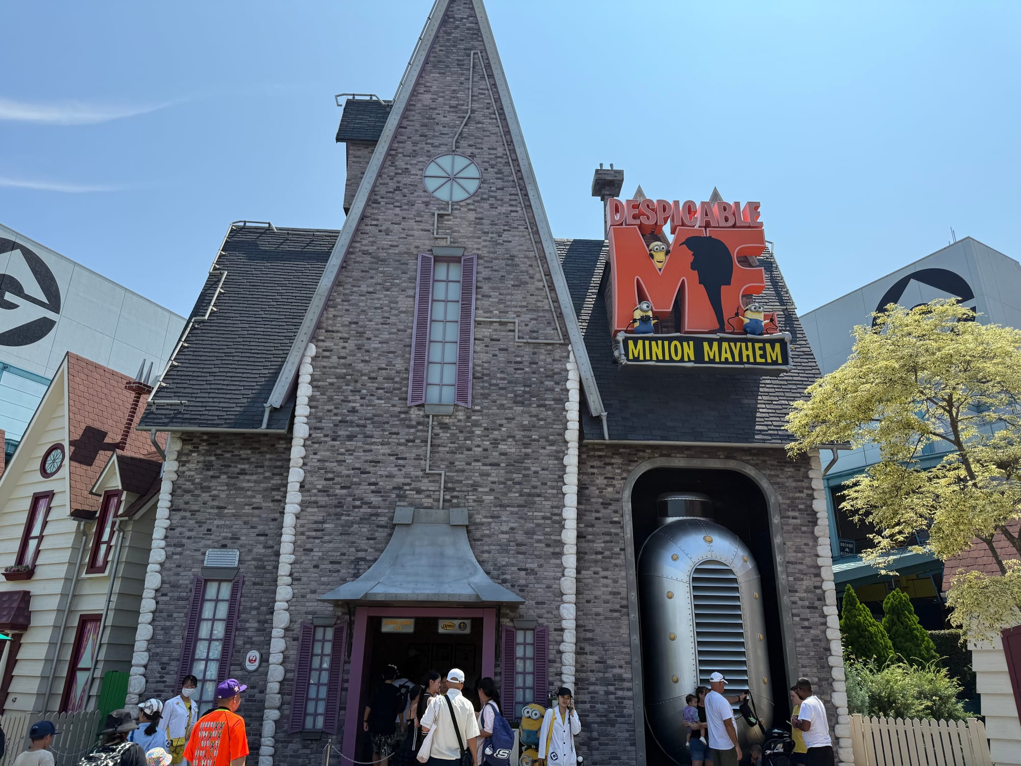 Entrance to Despicable Me: Minion Mayhem at Universal Studios Japan, featuring Gru's house façade, attraction signage and visitors entering the themed Minion attraction.