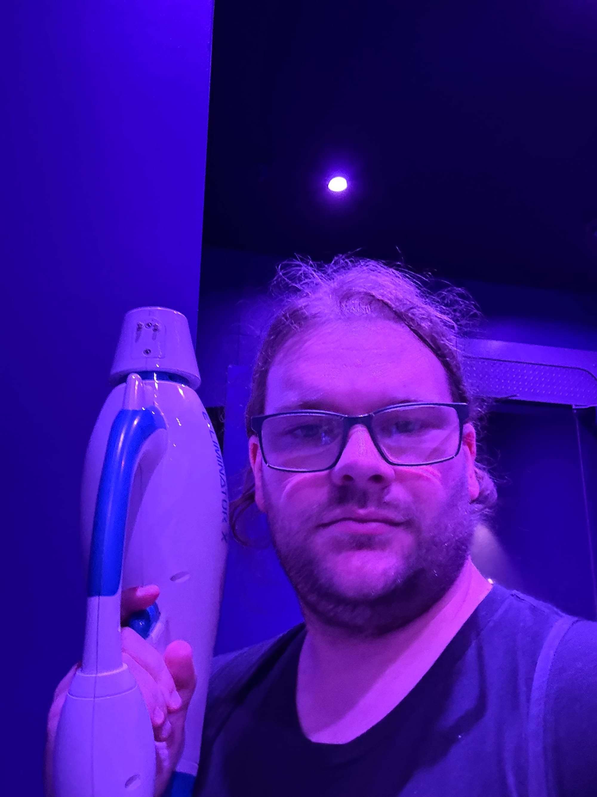 Visitor holding an interactive blaster inside Illumination's Villain-Con Minion Blast at Universal Studios Japan, illuminated by purple lighting before entering the attraction.