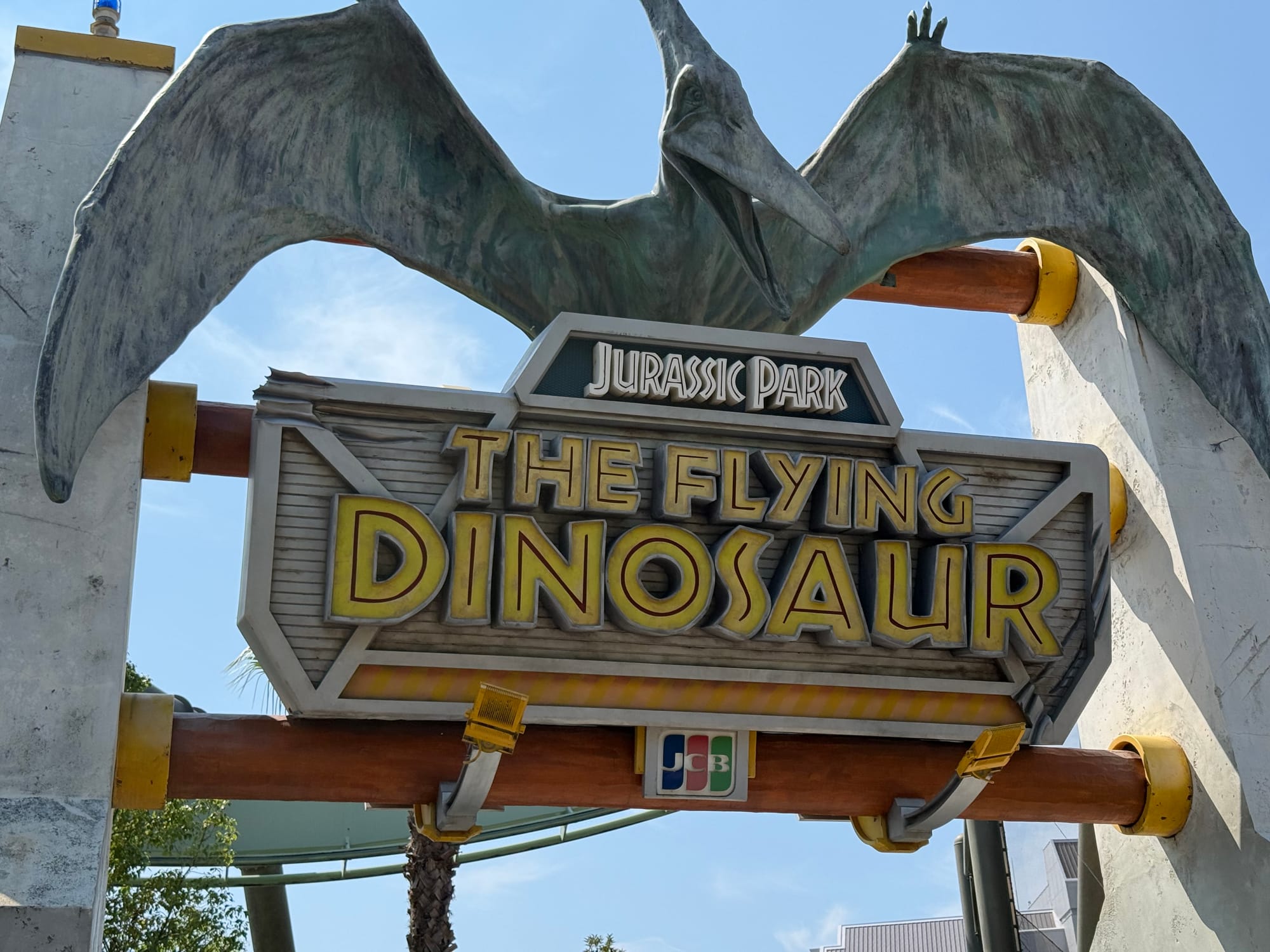 Entrance sign for The Flying Dinosaur at Universal Studios Japan, featuring a giant pterosaur perched above the attraction name and Jurassic Park branding.