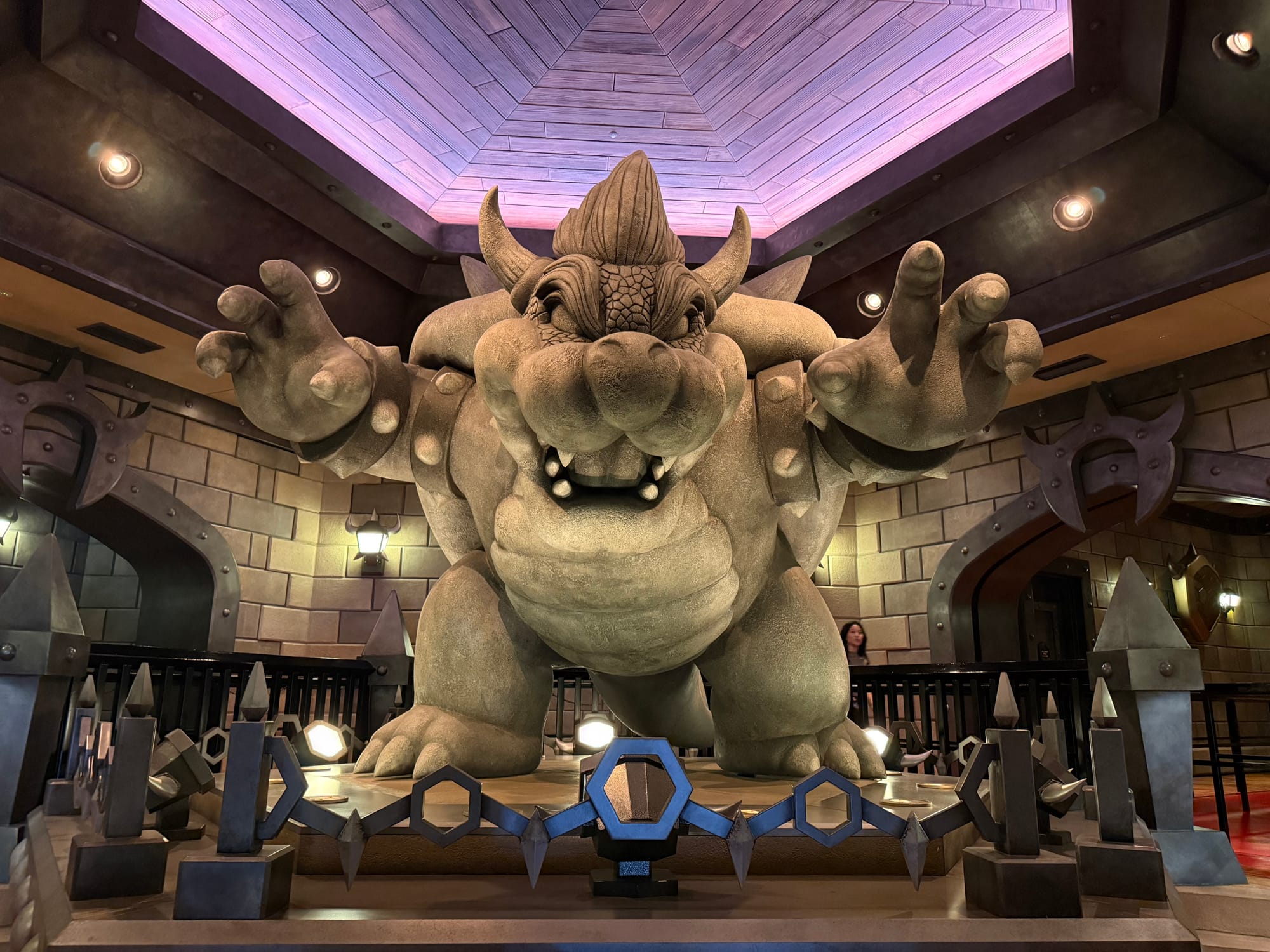 Large Bowser statue inside Mario Kart: Koopa's Challenge at Super Nintendo World, depicting the king of the Koopas reaching forward within a castle-themed queue area.