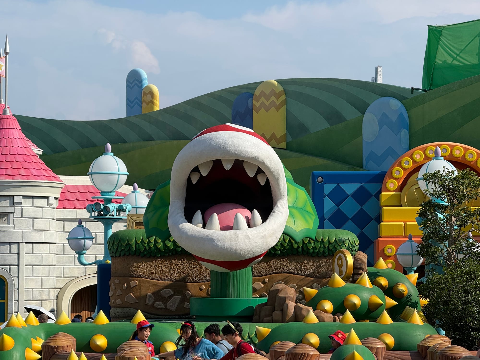 Piranha Plant character in Super Nintendo World at Universal Studios Japan, towering above themed scenery inspired by the Mushroom Kingdom, with visitors walking below.