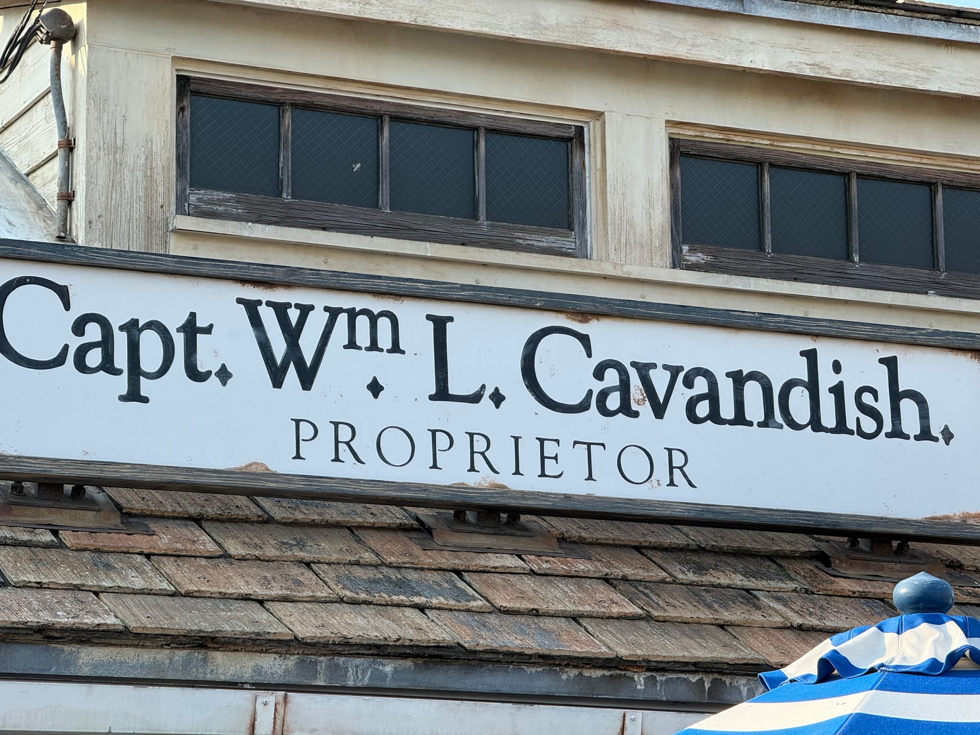 Sign reading "Capt. Wm. L. Cavandish, Proprietor" on a weathered waterfront-style building in Universal Studios Japan's Amity area, featuring rustic wooden details and aged décor.