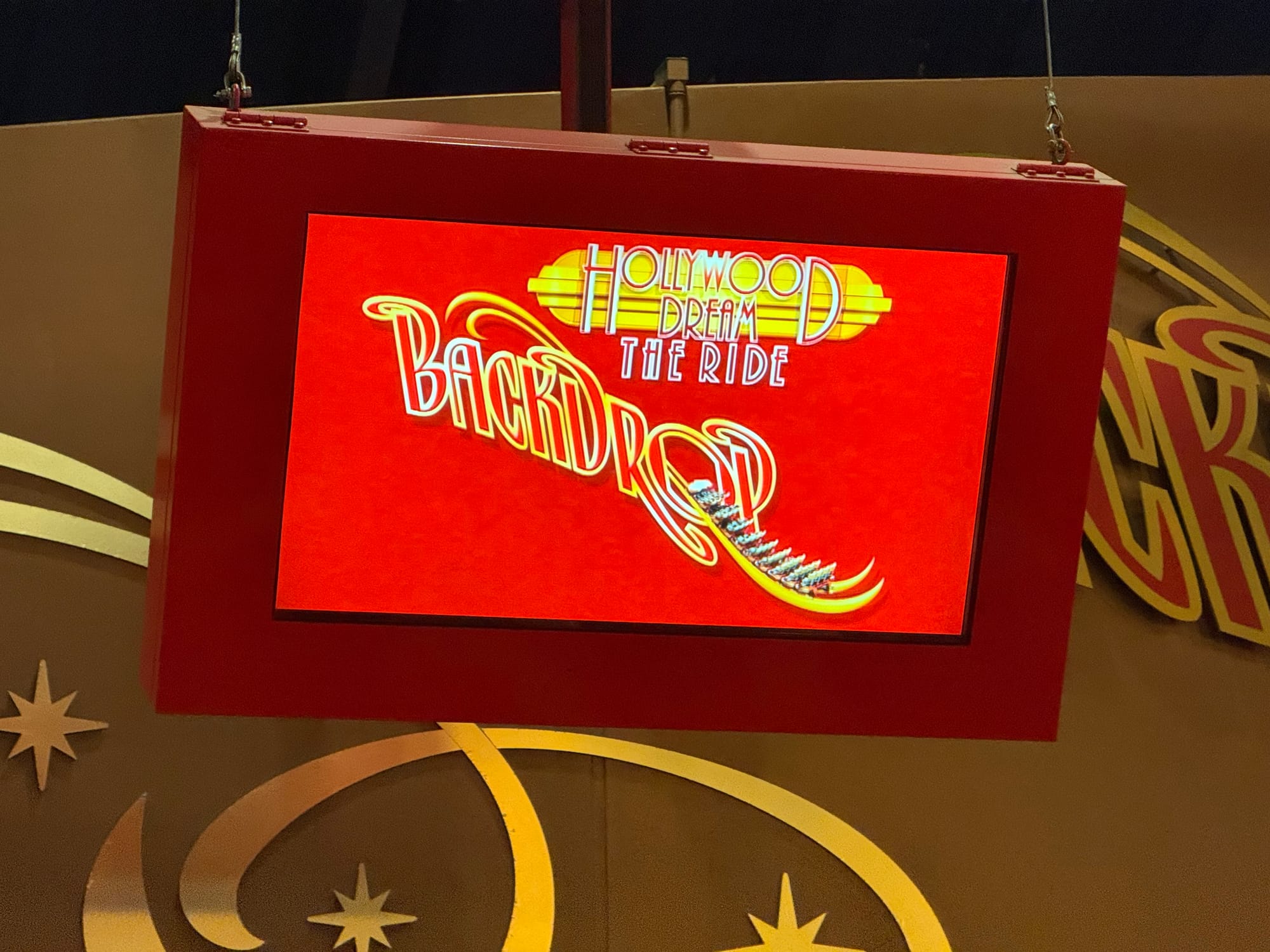 Display screen for Hollywood Dream: The Ride Backdrop at Universal Studios Japan, showing the attraction logo and backward-facing roller coaster train graphic in the queue area.