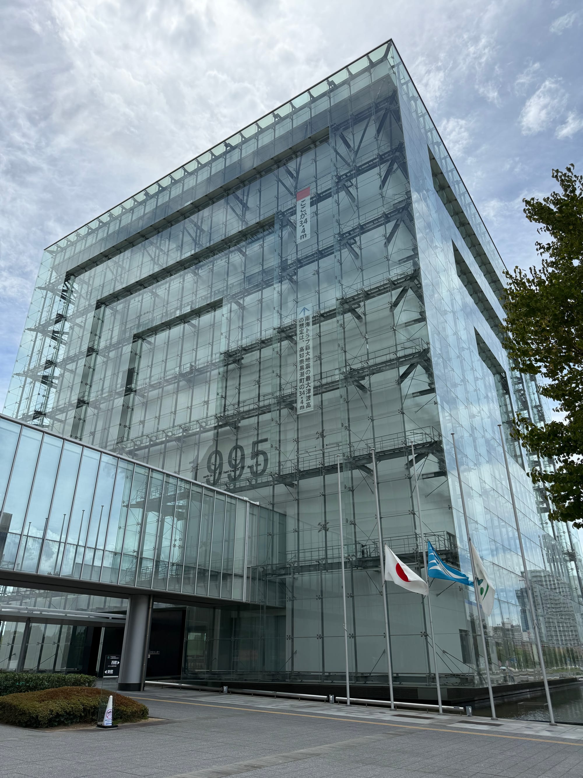 Great Hanshin-Awaji Earthquake Memorial building in Kobe, featuring a distinctive glass façade with the height of the 1995 earthquake fault displacement marked on the structure.