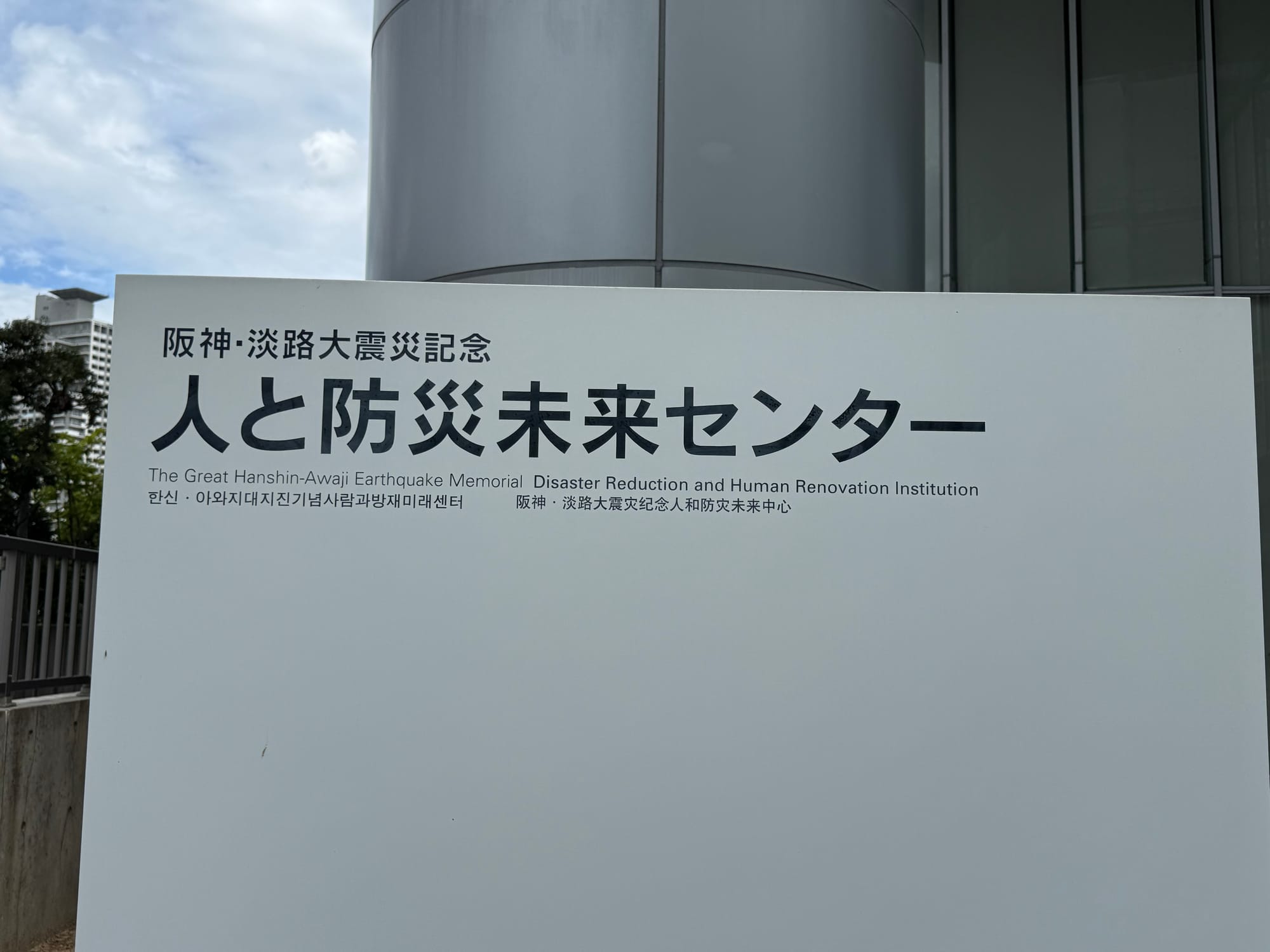 Sign for the Great Hanshin-Awaji Earthquake Memorial Disaster Reduction and Human Renovation Institution in Kobe, displayed outside the museum building with Japanese and English text.