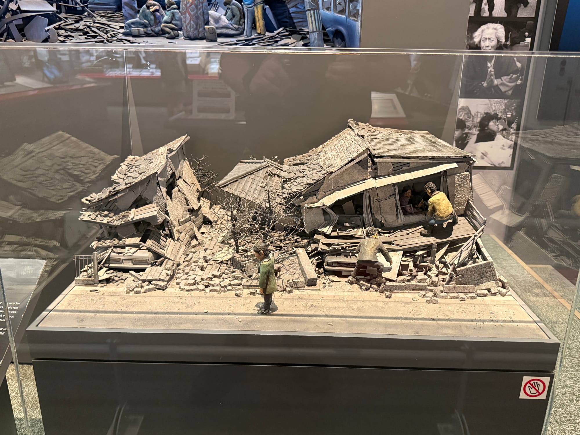 Diorama at the Great Hanshin-Awaji Earthquake Memorial depicting collapsed houses after the 1995 earthquake, with residents and rescuers navigating rubble-filled streets.