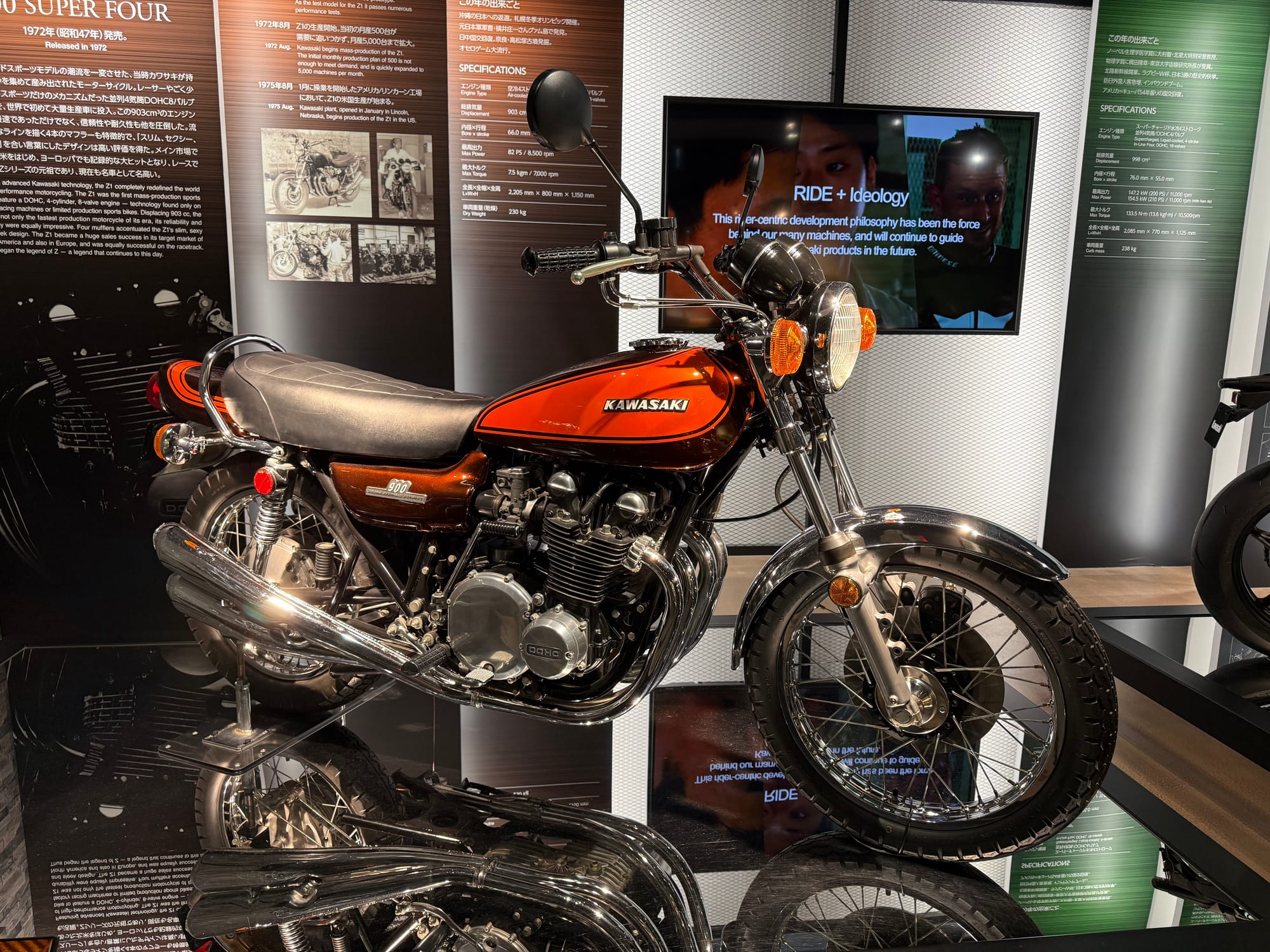 Kawasaki Z1 900 motorcycle displayed at Kawasaki Good Times World in Kobe, featuring orange-and-brown bodywork, a DOHC inline-four engine and classic 1970s styling.